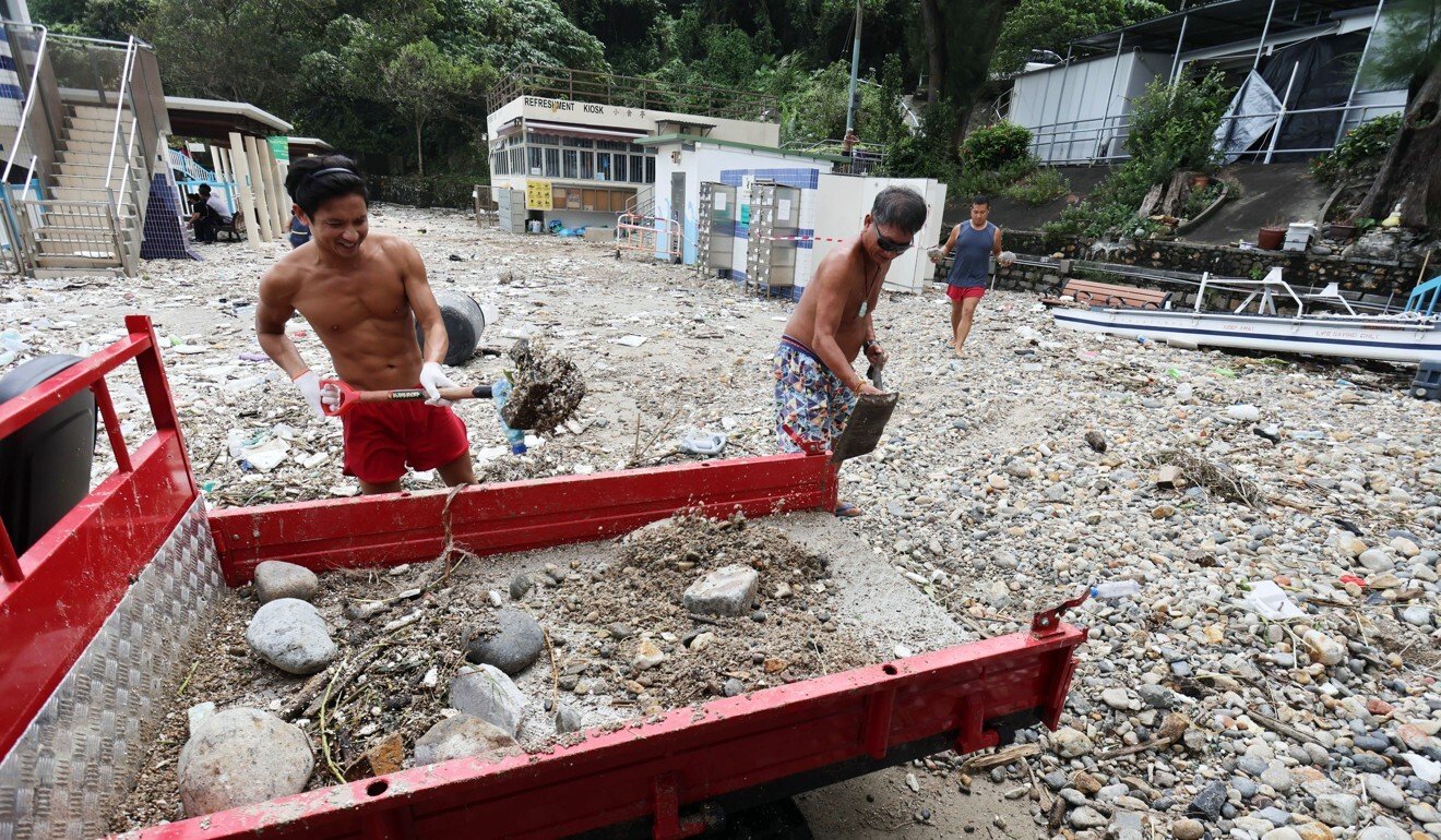 Two workers begin removing debris from Silverstrand Beach. Photo: May Tse