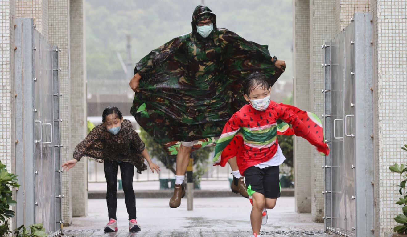 A father and his two children run through the rain at Heng Fa Villa in Chai Wan on Hong Kong Island on Wednesday. Photo: Dickson Lee