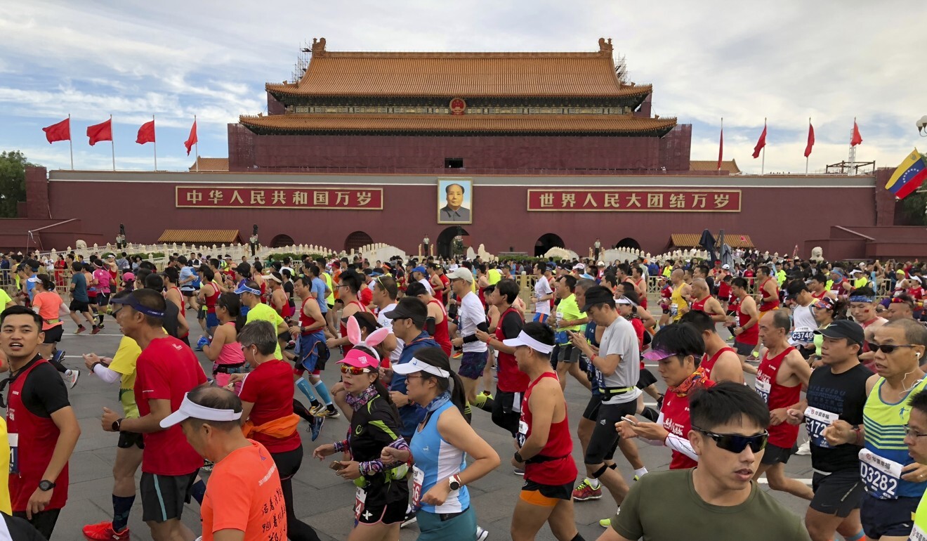 Runners pass by the large portrait of Chinese leader Mao Zedong on Tiananmen Gate near Tiananmen Square at the start of the 2018 Beijing Marathon. Photo: AP