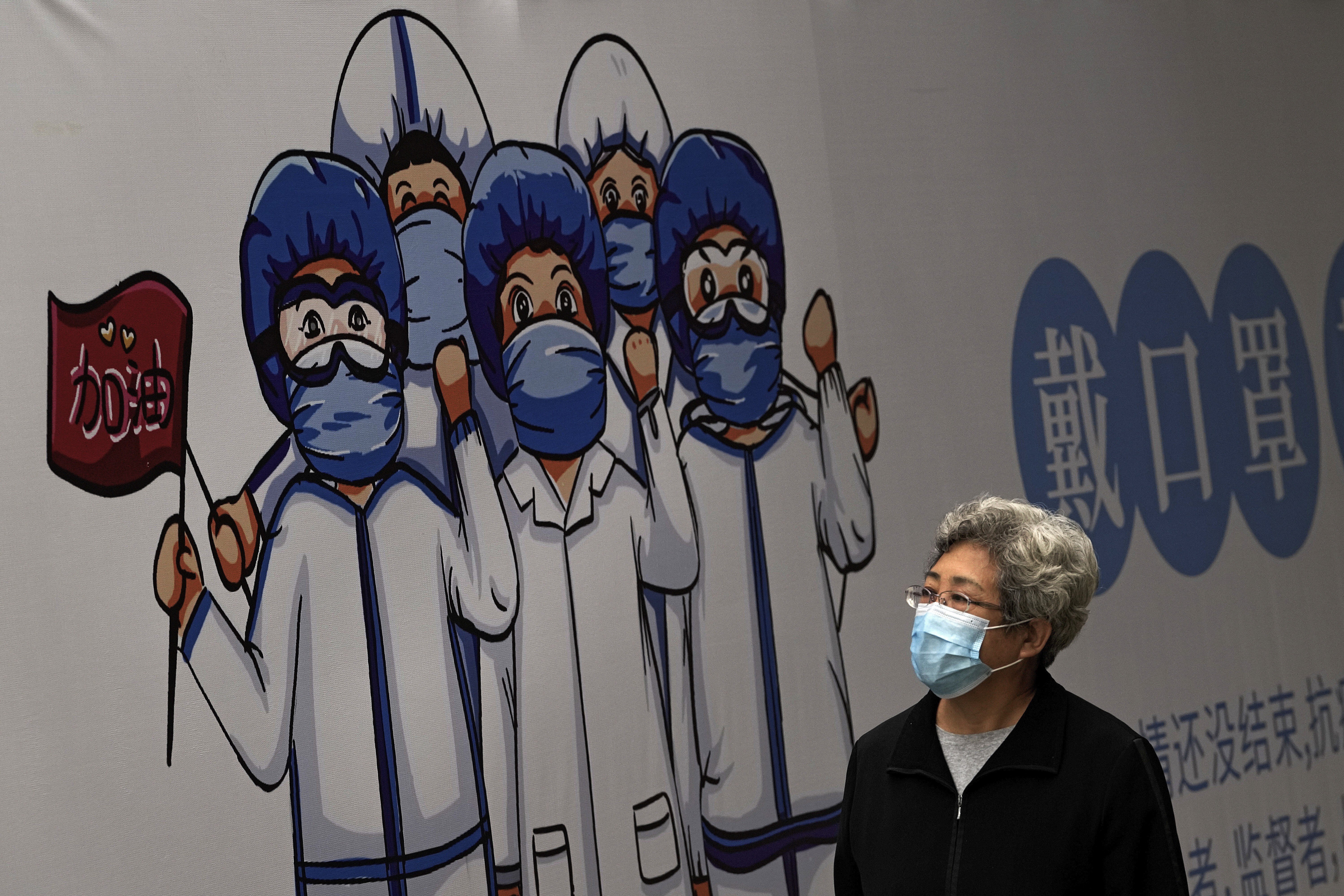A woman walks past a billboard depicting medical workers in Beijing. Photo: AP