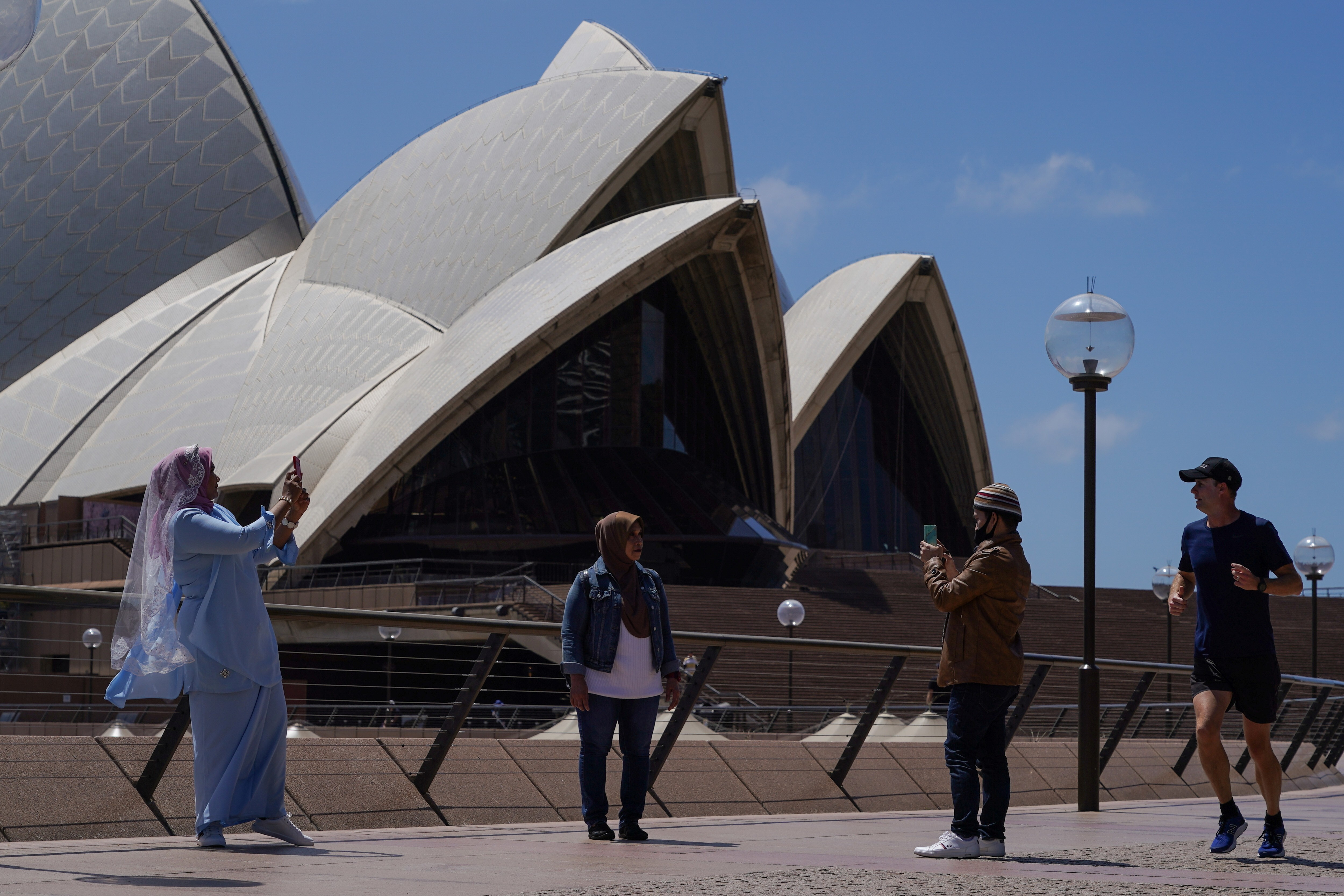 People take pictures in front of the Opera House in Sydney, Australia. Photo: Reuters