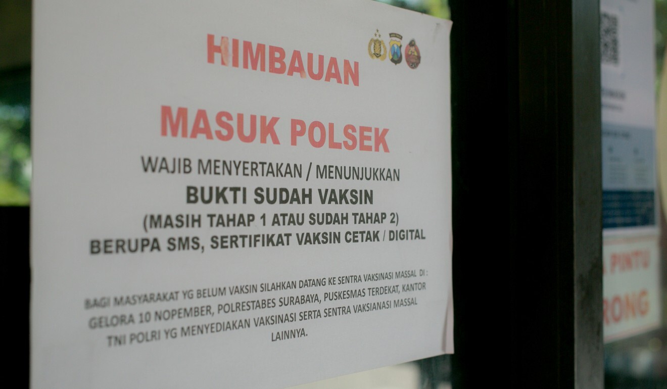 A sign on the window of Wonocolo Police Station in Surabaya states that proof of vaccination is mandatory to enter. Photo: Ivan Darski