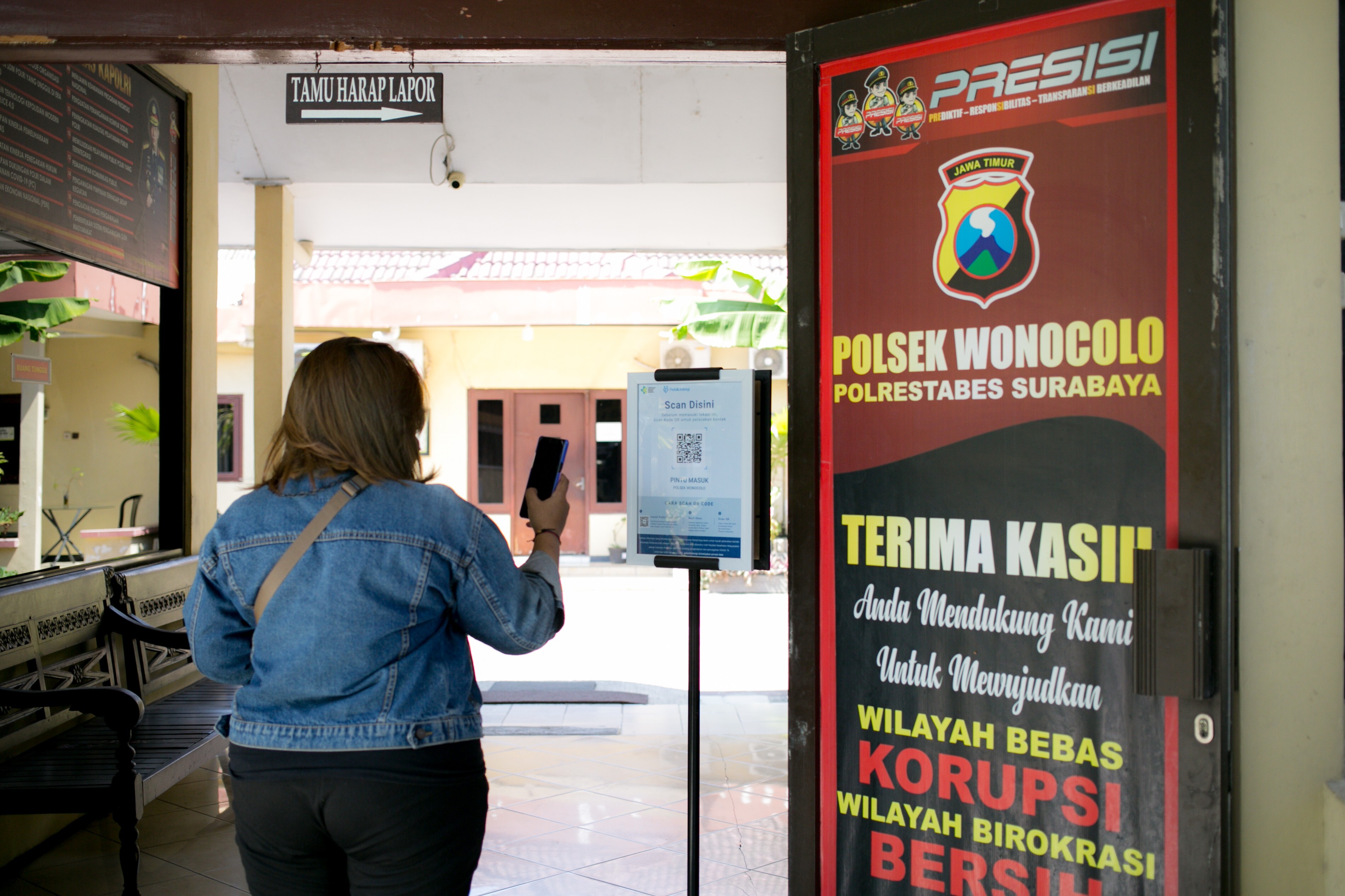 A visitor to the Wonocolo Police Station in Surabaya, Indonesia, scans their vaccine information before entering. Photo: Ivan Darski