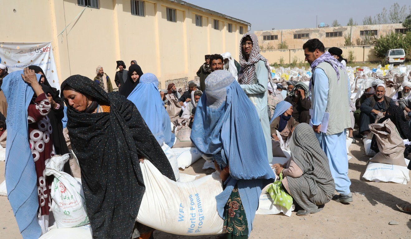Women carry food rations as they leave a World Food Programme distribution point on the outskirts of the city of Herat, Afghanistan. Photo: Handout