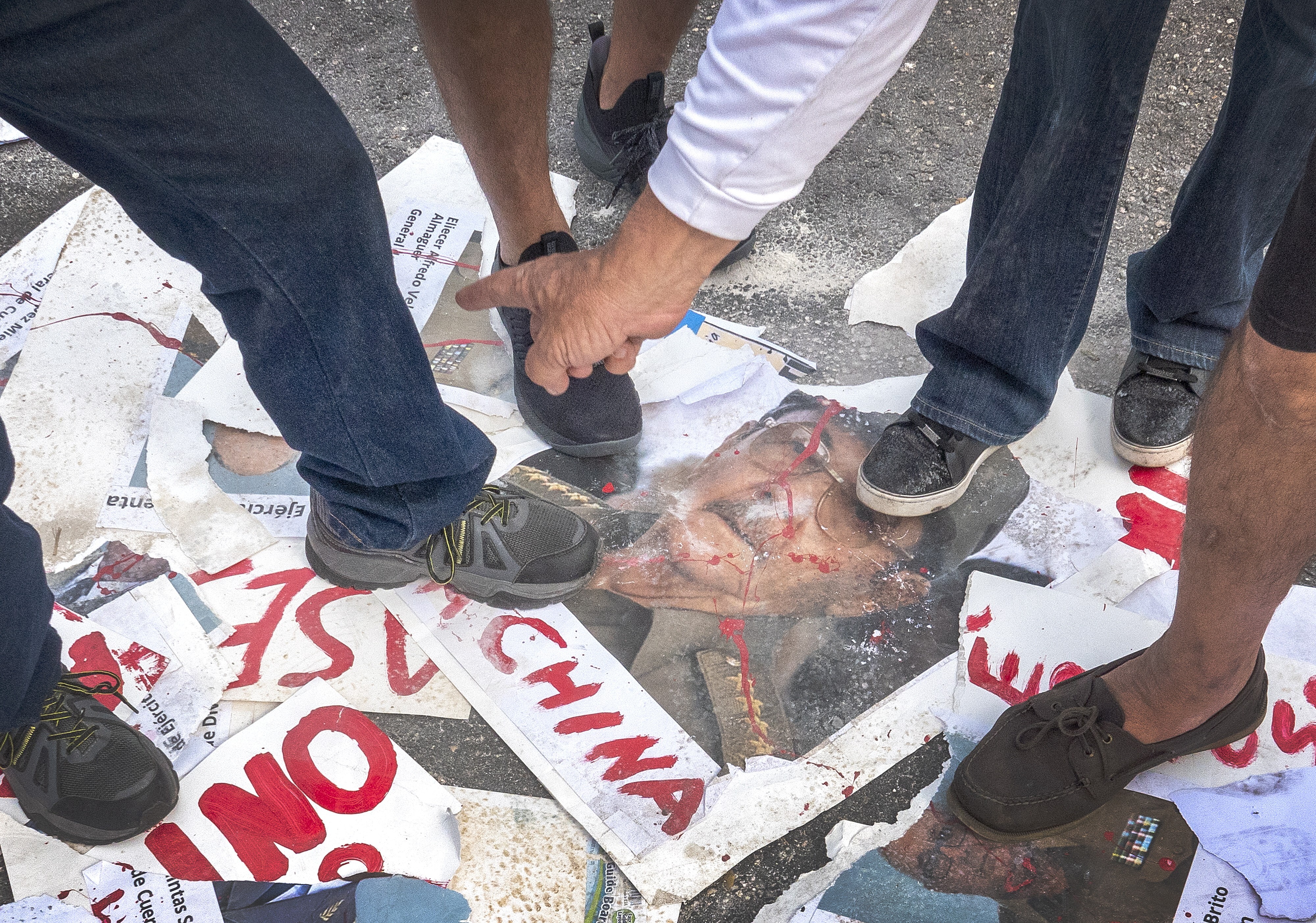 Cuban exiles and freedom activists rip photos of former Cuban president Raul Castro during a demonstration in Miami, Florida. Photo: EPA
