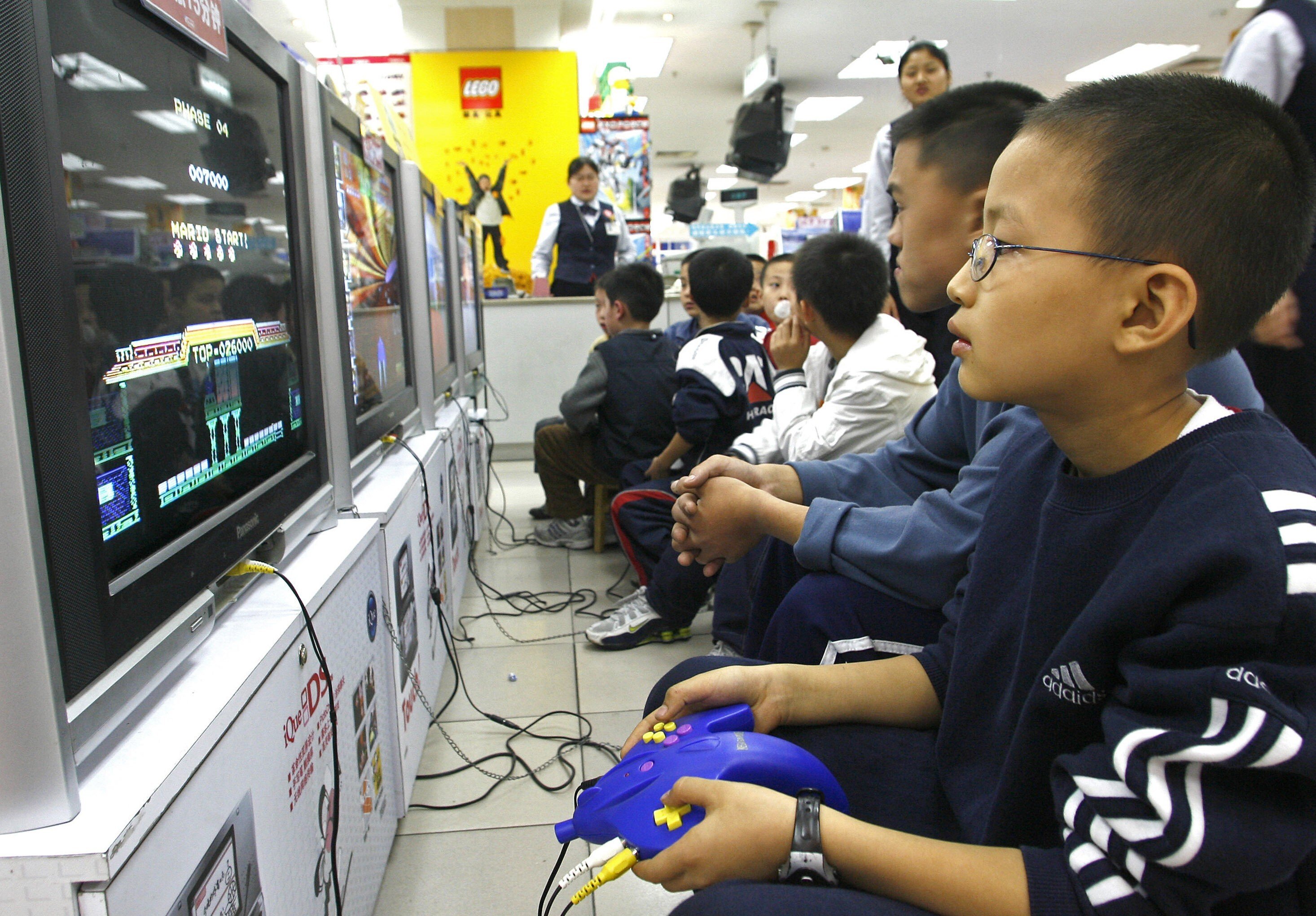 Children play the video games on TVs at a shopping centre in Chengdu, in China's southwestern Sichuan province, on October 30, 2006. The Chinese government has long had an uncomfortable relationship with video games, and it ramped up restrictions for minors again this year. Photo: AFP