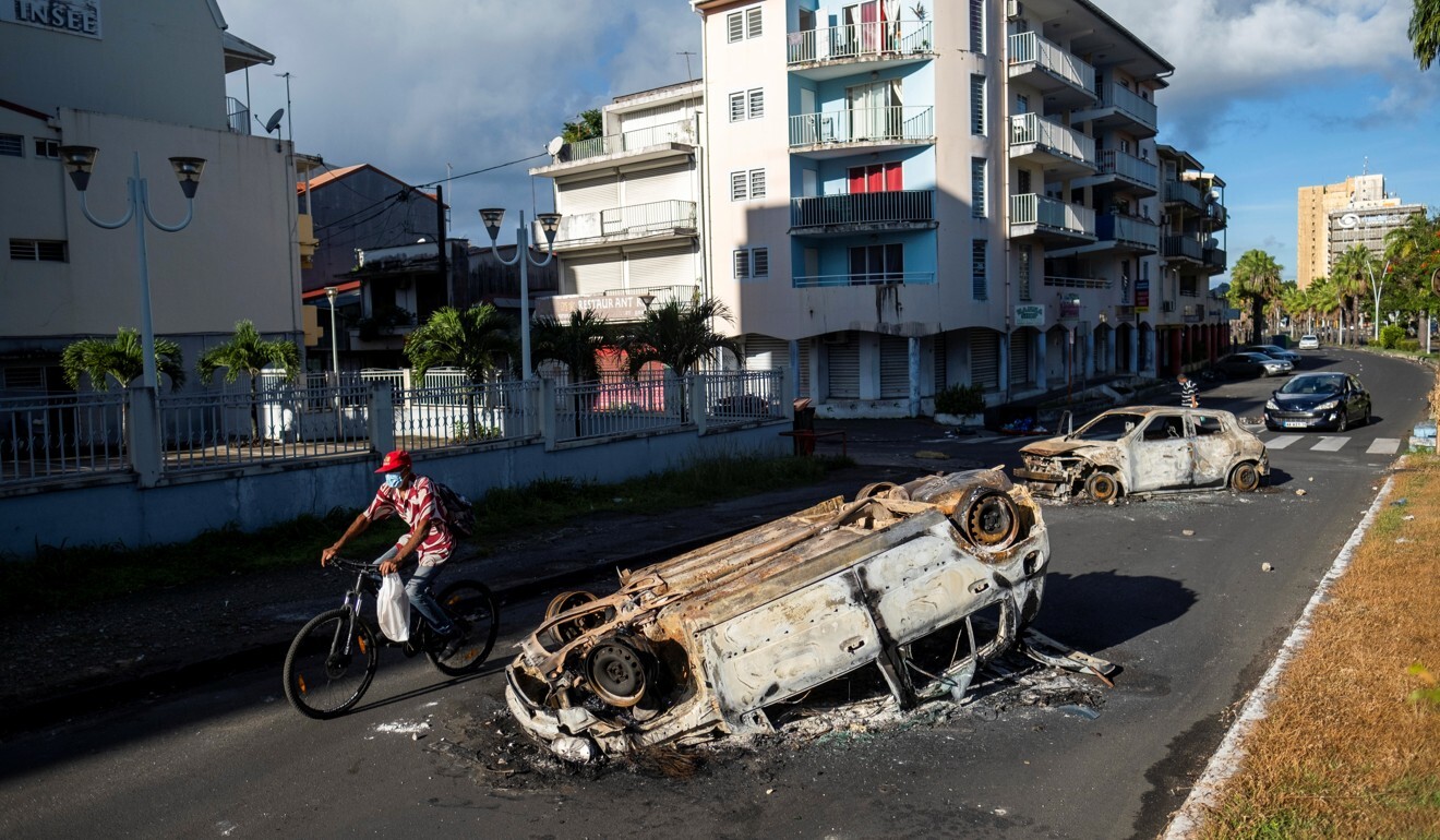 Burned cars seen on a street after violent demonstrations took place over coronavirus protocols in Pointe-a-Pitre, Guadeloupe. Photo: Reuters