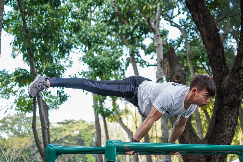 Lam Chi-long does a straddle planche lean on the monkey bars in Victoria Park.