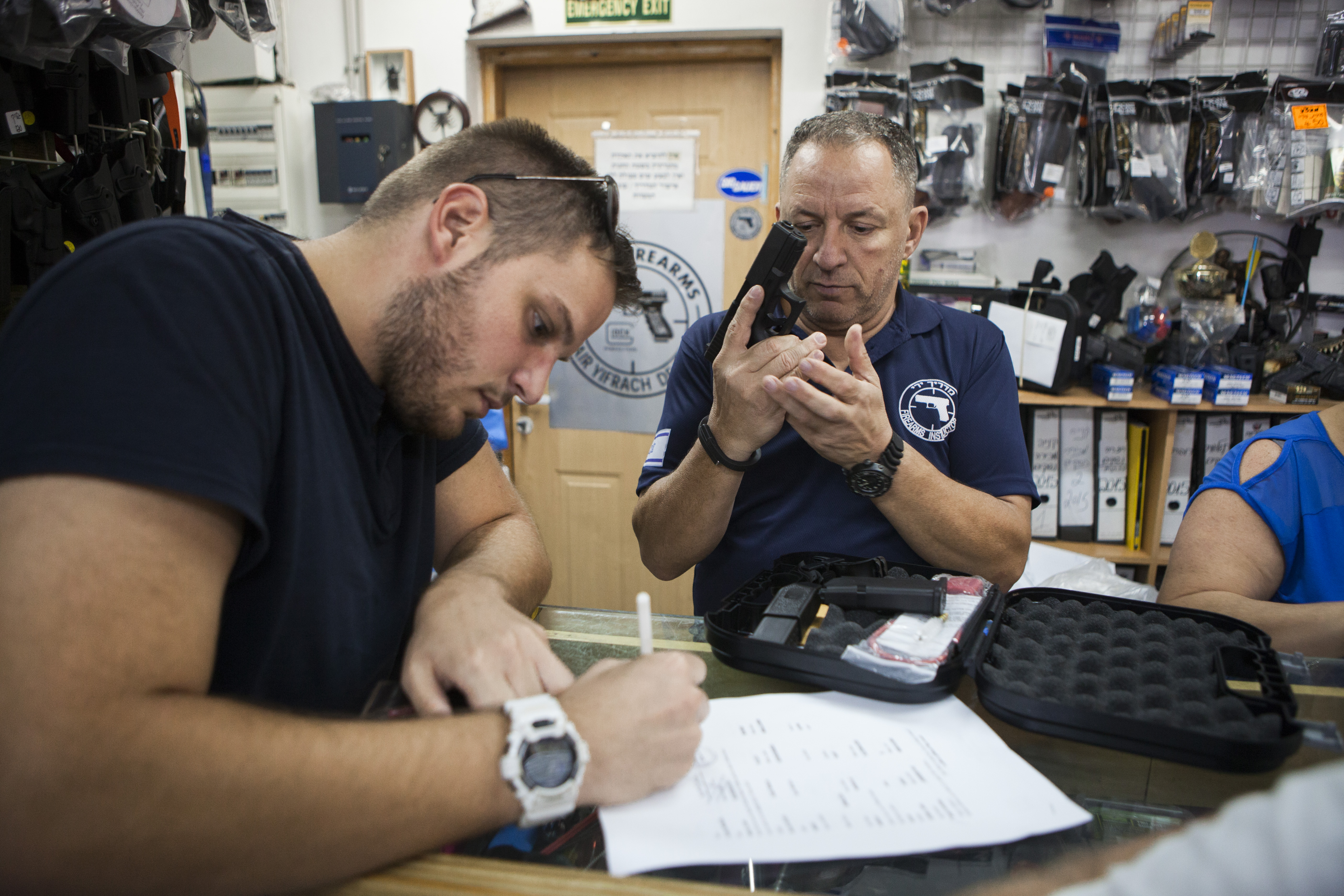 An Israeli man buys a gun in a weapons shop near the West Bank Jewish settlement of Givat Zeev, Sunday, Oct. 11, 2015. Jerusalem's mayor, caught on video last week with a gun slung over his shoulder while visiting a Palestinian neighborhood, made no apologies Friday for the display of force. He said he's helping keep his city safe. Store owners have said sales of guns and pepper spray are soaring. (AP Photo/Dan Balilty)