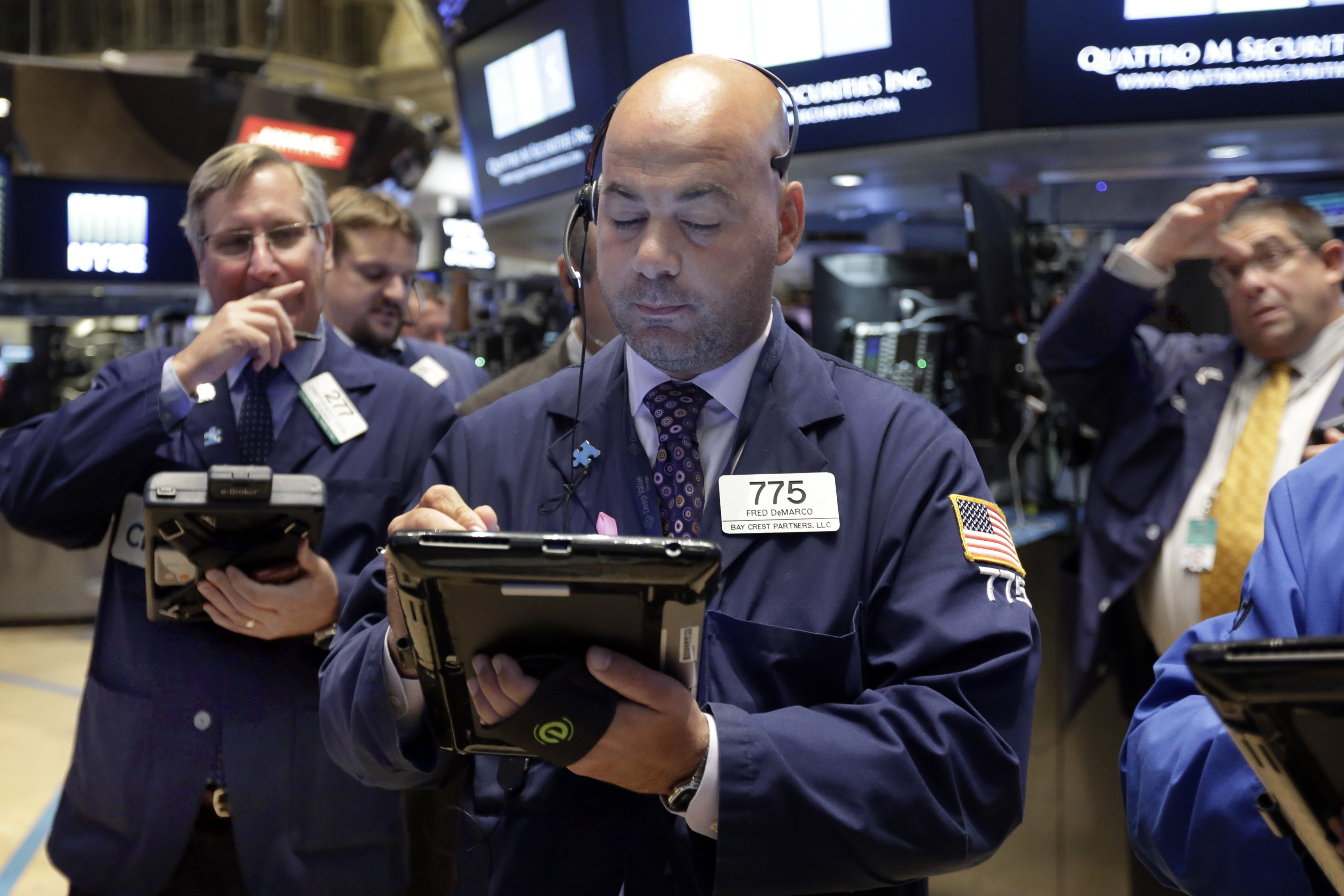 Trader Fred DeMarco, center, works on the floor of the New York Stock Exchange, Monday, Oct. 12, 2015. Stocks are little changed in early trading as traders look ahead to the start of corporate earnings season. (AP Photo/Richard Drew)