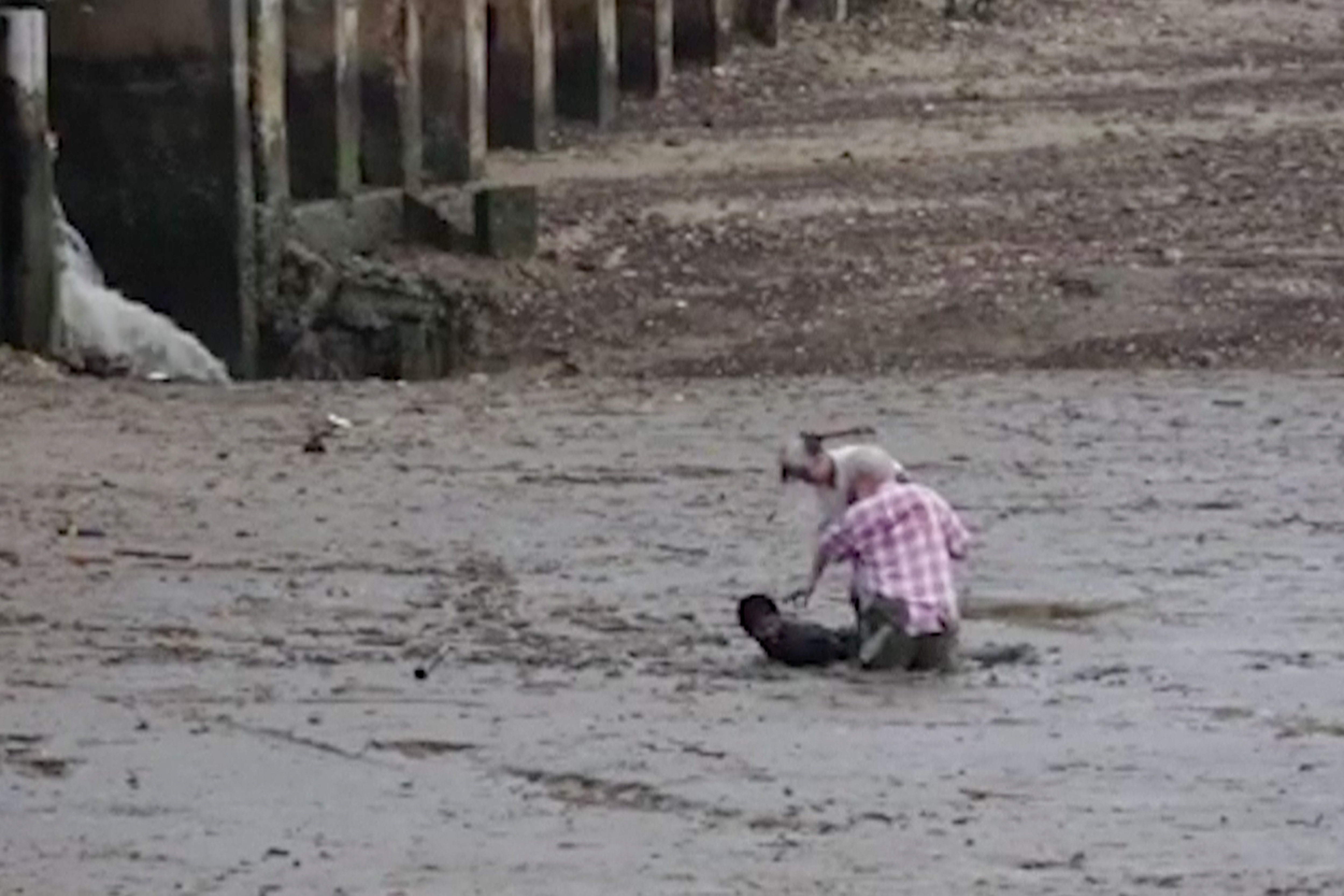 In this image made from video provided by Theerasak Saksritawee, Thai construction worker Chat Ubonchinda lies in the mud as he helps two unidentified Norwegian bird watchers who were sinking into a mudflat in Krabi, southern Thailand, Friday, Oct. 16, 2015. Chat lay down in the mud to allow the pair to use his body to pry themselves to safety. (Theerasak Saksritawee via AP) NO ARCHIVE, MANDATORY CREDIT