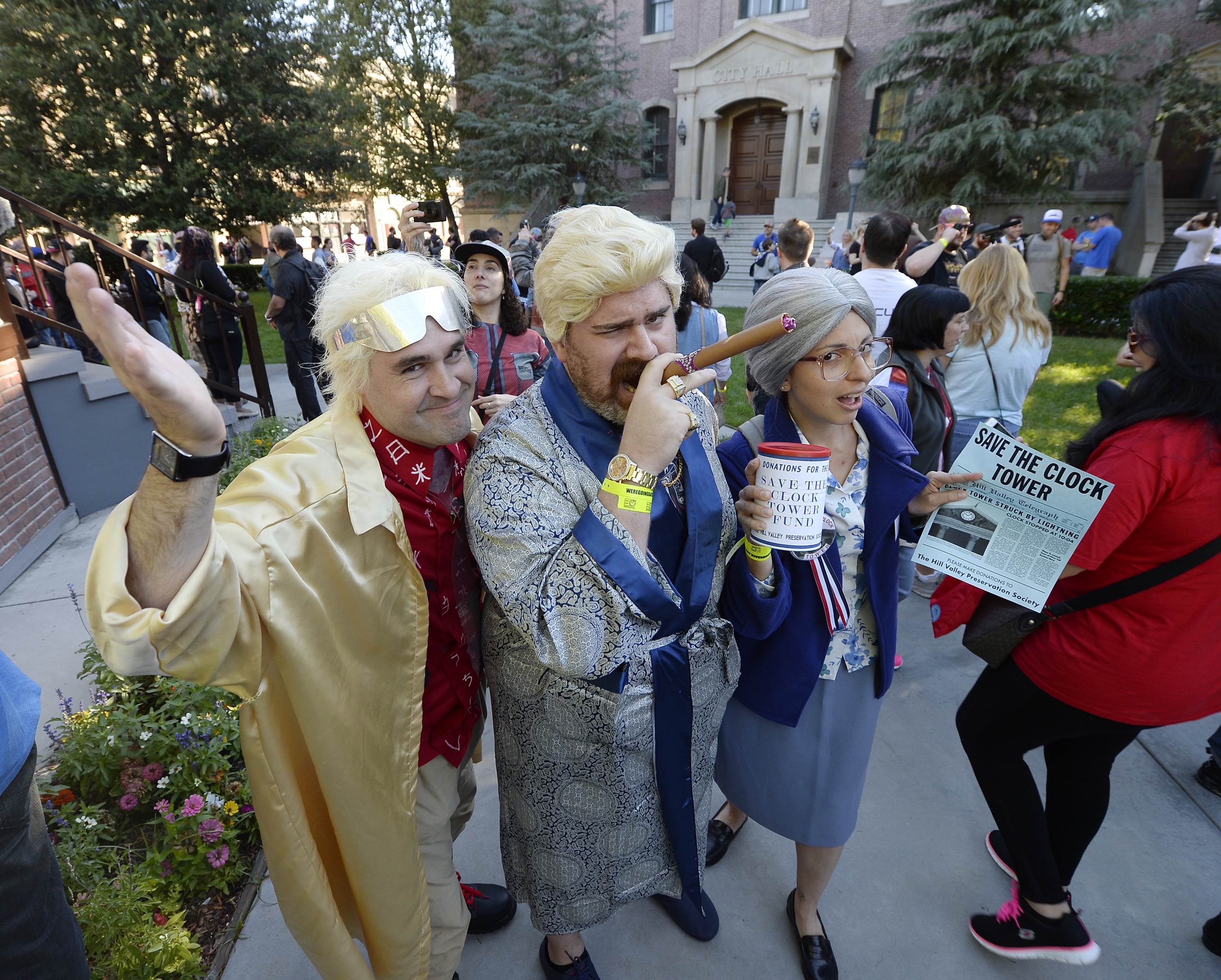 UNIVERSAL CITY CA - OCTOBER 21: Vinnie Donadio (L), dressed as the character Dr. Emmett Brown, Mike D'Amico, dressed as alternate 1985 rich Biff (C), and Cristina Fanti, as Hill preservation society lady, pose in the Hill Valley Courthouse square in the back lot of Universal Studios during "Back To The Future" day October 21, 2015 in Universal City, California. Kevork Djansezian/Getty Images/AFP == FOR NEWSPAPERS, INTERNET, TELCOS & TELEVISION USE ONLY ==