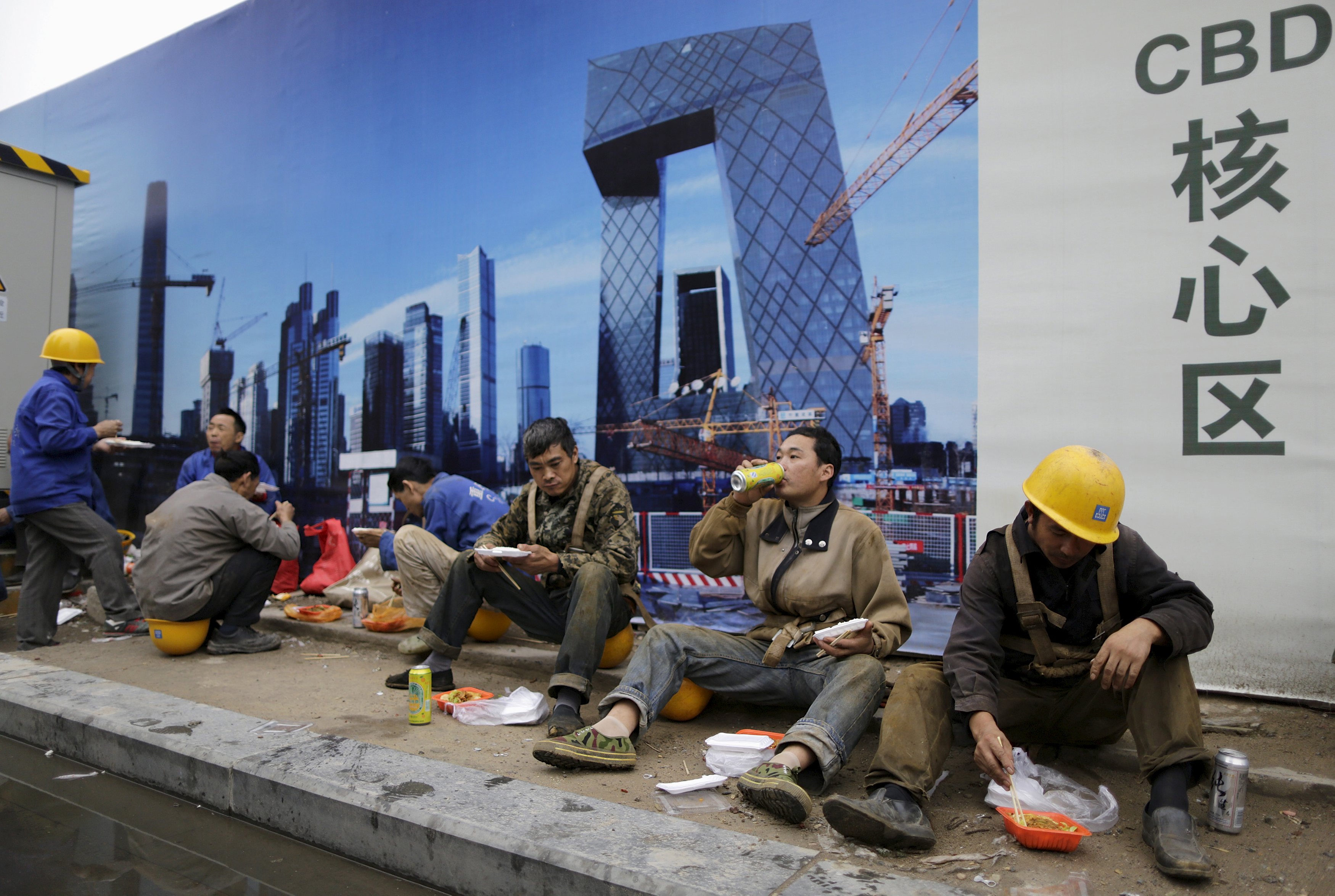 Construction workers have lunch as they sit in front of a poster bearing a picture of the Central Business District (CBD) area, outside a construction site in Beijing, China, October 26, 2015. China's ruling Communist Party opened a key meeting on Monday that will focus on financial reforms and how to maintain growth of around seven percent and more broadly map out economic and social targets for the next five years. REUTERS/Jason Lee