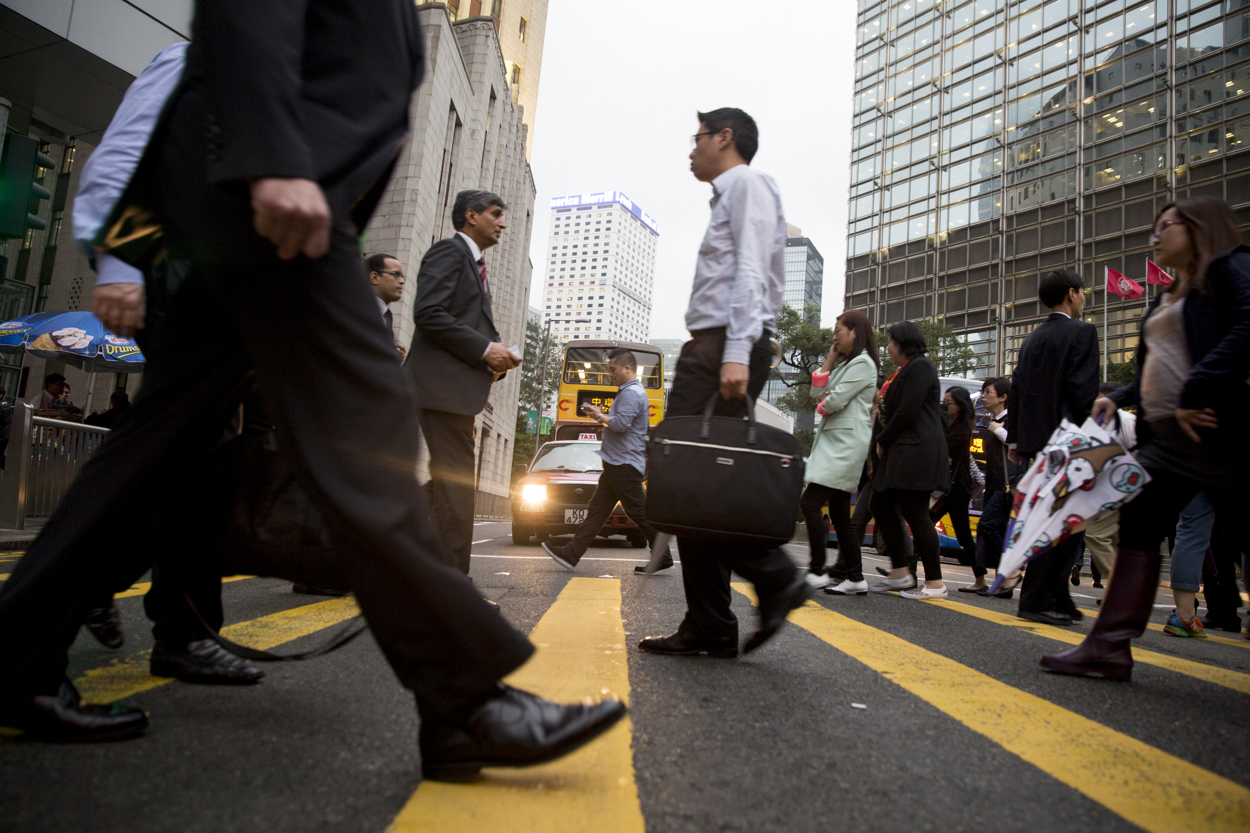 Pedestrians cross a street in the Central district of Hong Kong, China, on Wednesday, April 2, 2014. Emissions from transportation may rise at the fastest rate of all major sources through 2050, the United Nations will say in a report due April 13. Heat-trapping gases from vehicles may surge 71 percent from 2010 levels, mainly from emerging economies, according to a leaked draft of the most comprehensive UN study to date on the causes of climate change. Photographer: Brent Lewin/Bloomberg