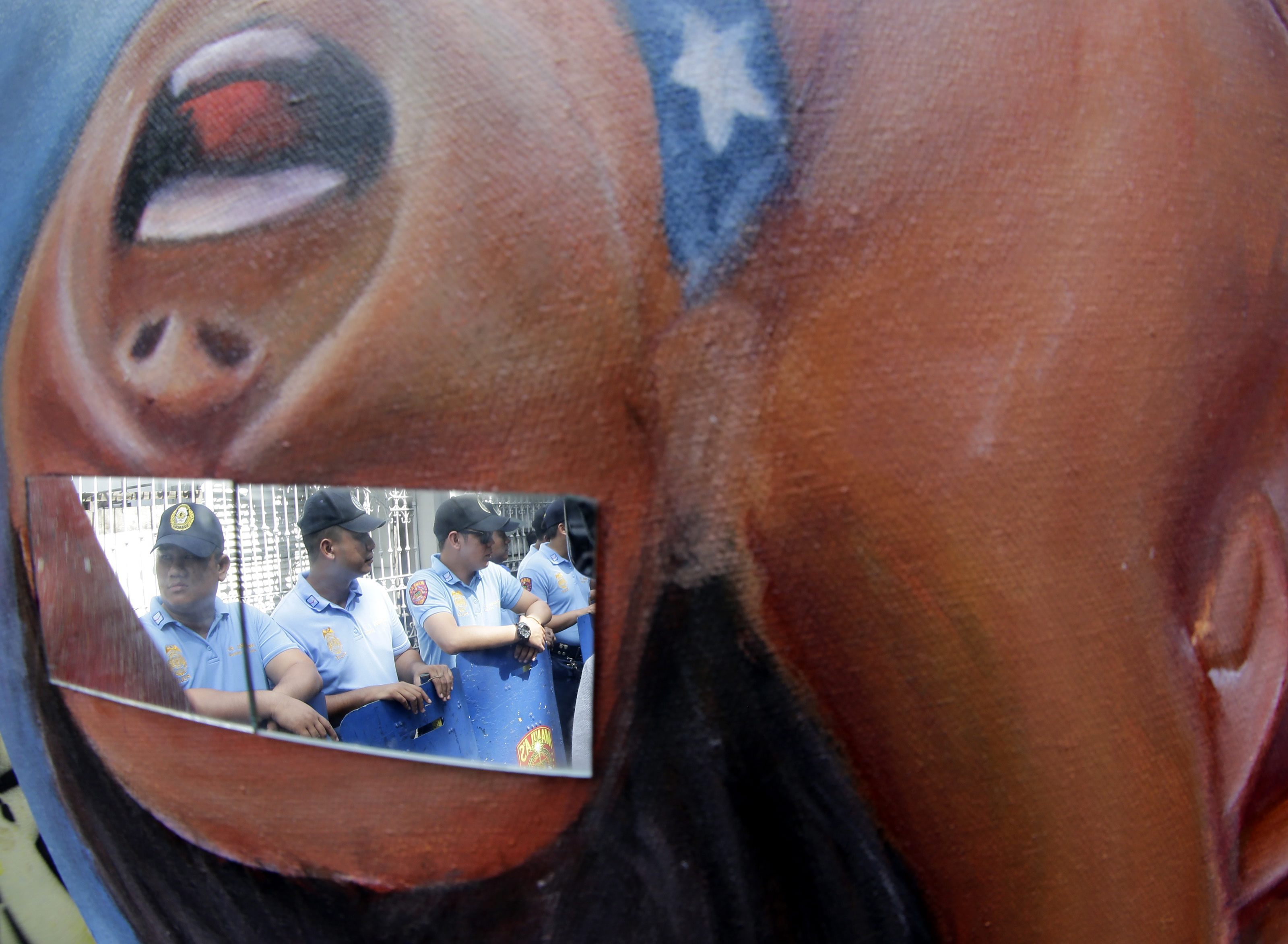 epa05018970 Filipino anti riot police are refected on a glass mounted on a protest placcard during a picket in front of the Philippine Supreme Court to coincide with its en banc session on the constitutionality of the Enhanced Defense Cooperation Agreement (EDCA) in Manila, Philippines, 10 November 2015. According to the statement of the protesters, they alledged that the EDCA will be presented as a gift to President Barack Obama when he visits the country to attend the APEC (Asia-Pacific Economic Cooperation) Summit. The Philippines will hosts the meetings starting November 12, with the summit on November 18-19. President Benigno Aquino III will host a welcome dinner for the leaders of the 21 member countries on November 18. EPA/FRANCIS R. MALASIG