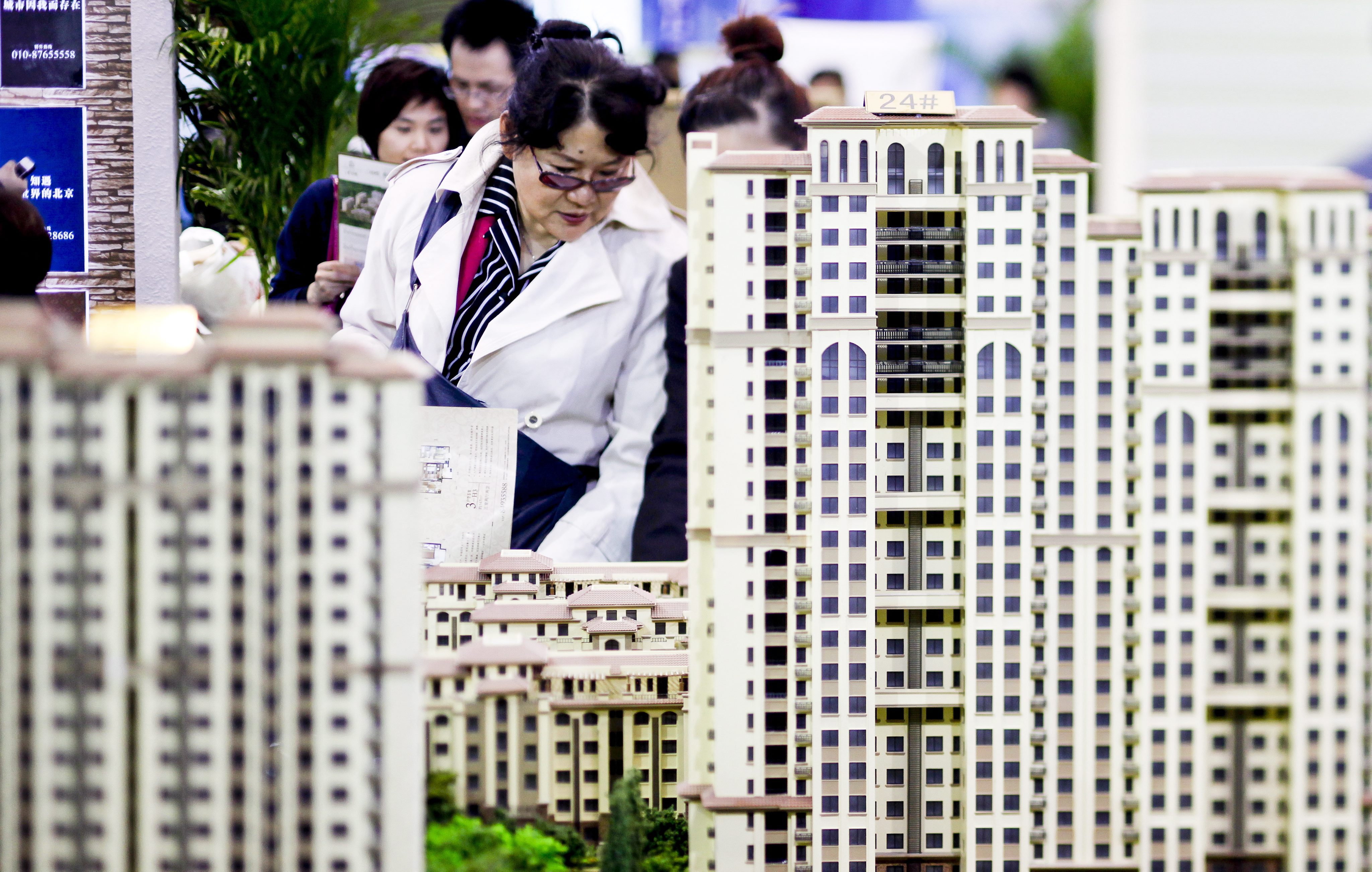 epa03172257 A picture taken with a tilt-shift lens shows people looking at models of new residential developments for sale at a real estate fair in Beijing, China, 05 April 2012. Chinese Premier Wen Jiabao said 02 April that the government will continue to enforce restrictions on the country's property market, as home prices are still far from a reasonable level. China's home property prices in March fell 0.3 percent compared to February, according to market data. EPA/DIEGO AZUBEL