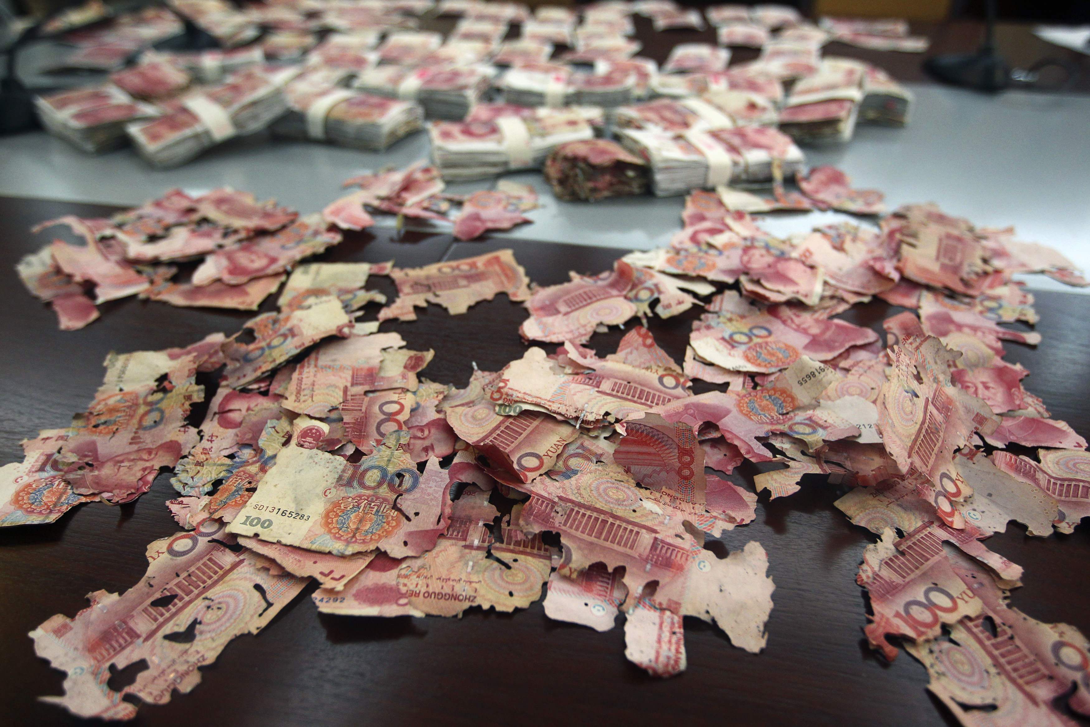 Damaged 100 yuan banknotes are seen on a table at a branch of China Bank in Foshan, Guangdong province, June 5, 2013. A woman brought about 400,000 yuan ($65,200), which she had kept at home, to the bank for replacement after most of the notes were bitten by white ants. Her notes were exchanged for new ones but for 60,000 yuan ($9,780) which the bank assessed and declared to be unchangeable. Picture taken June 5, 2013. REUTERS/Stringer (CHINA - Tags: BUSINESS SOCIETY TPX IMAGES OF THE DAY) CHINA OUT. NO COMMERCIAL OR EDITORIAL SALES IN CHINA