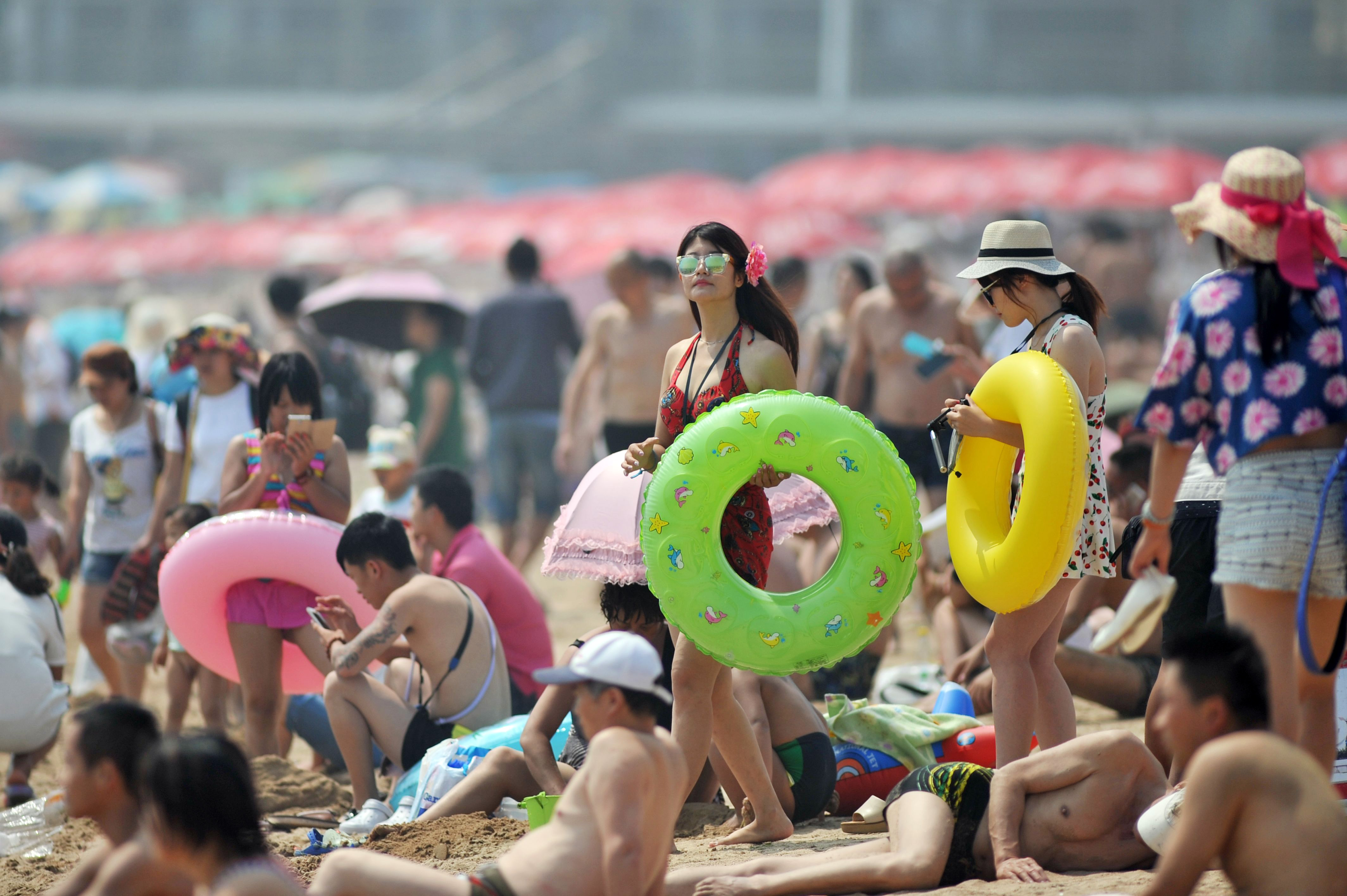 Visitors crowd a seaside beach on the first day this summer that it was open to the public in Qingdao in eastern China's Shandong province Wednesday, July 1, 2015. China's beaches are a popular destination for its citizens to escape the summer heat. (Chinatopix Via AP) CHINA OUT