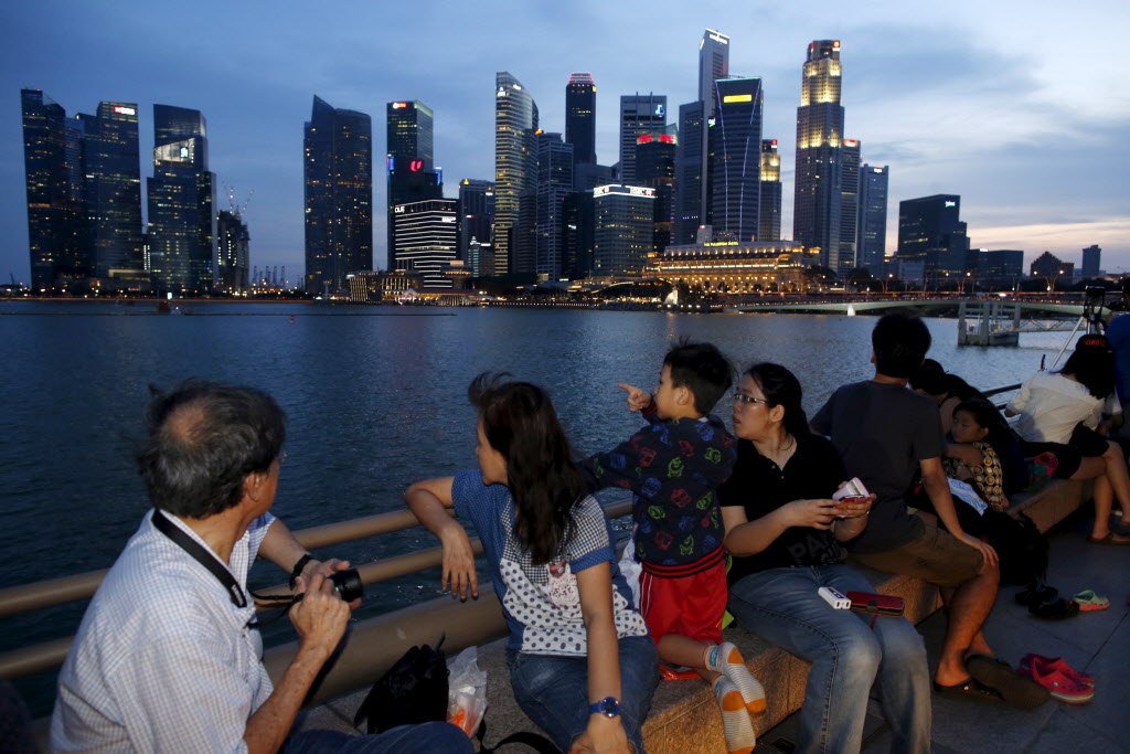 People wait for fireworks during a Golden Jubilee National Day Parade rehearsal along the Marina Bay overlooking the skyline of the central business district in Singapore July 25, 2015. Singapore holds a Jubilee weekend from 7 to 10 August to celebrate the 50th anniversary of its independence. Fifty years ago, hundreds of small boats lined the Singapore river in the city centre. Today, most small boats are gone, except a handful of neon-lit tourist ferries. Maritime trade is still the backbone of the city-state but after decades of rapid growth Singapore, which at less than half the size of London is among the world’s most densely populated nations, is also a popular tourist destination and a thriving global financial hub. REUTERS/Edgar Su