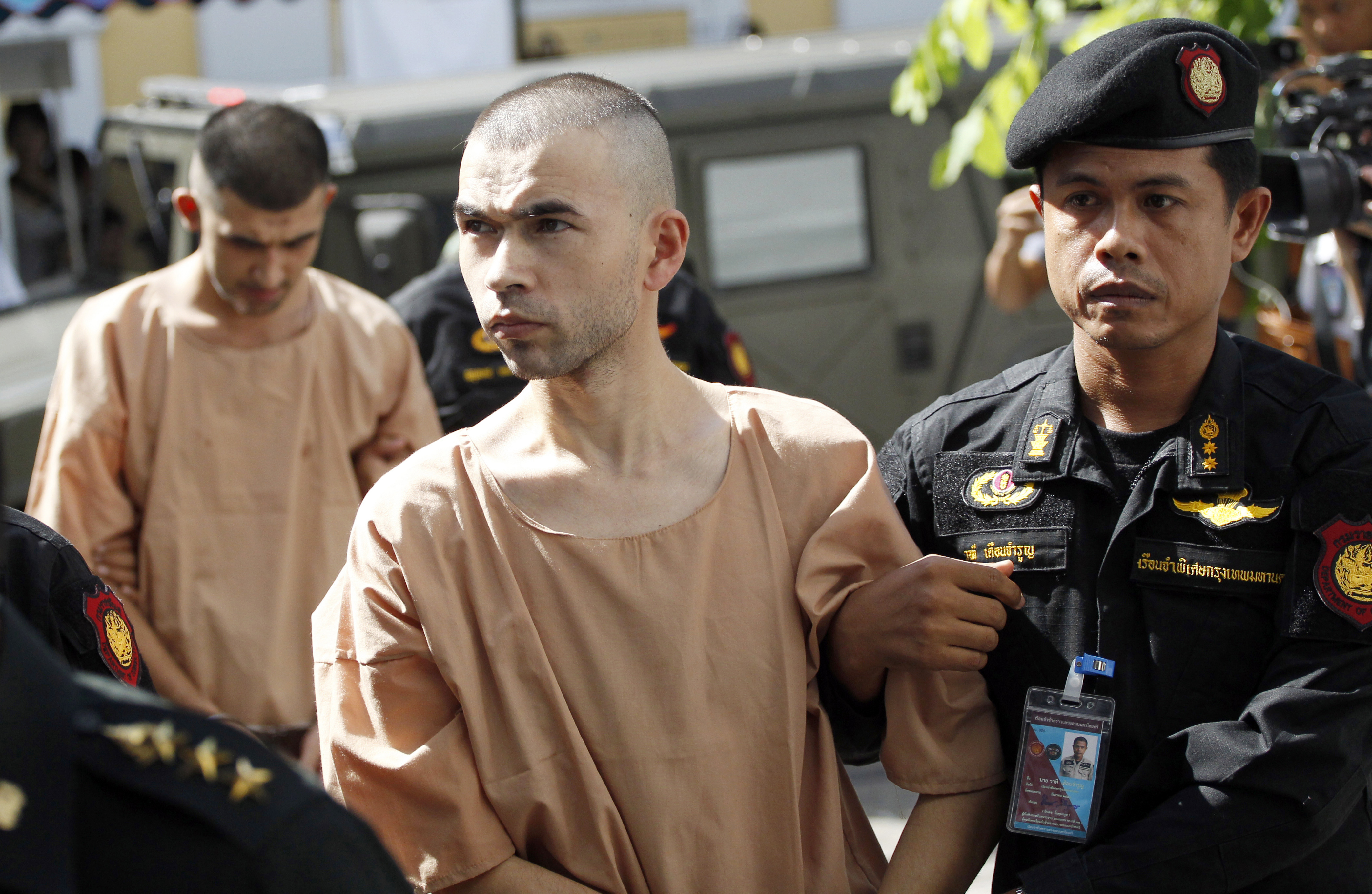 Police officers escort suspects in the Aug. 17 blast at Erawan Shrine, Bilal Mohammad, front, and Mieraili Yusufu, rear, as they arrive at a military court in Bangkok, Thailand, Tuesday, Nov. 24, 2015. The military court has indicted two men police say carried out the deadly August bombing at the shrine that left 20 people dead and more than 120 injured. (AP Photo/Sakchai Lalit)