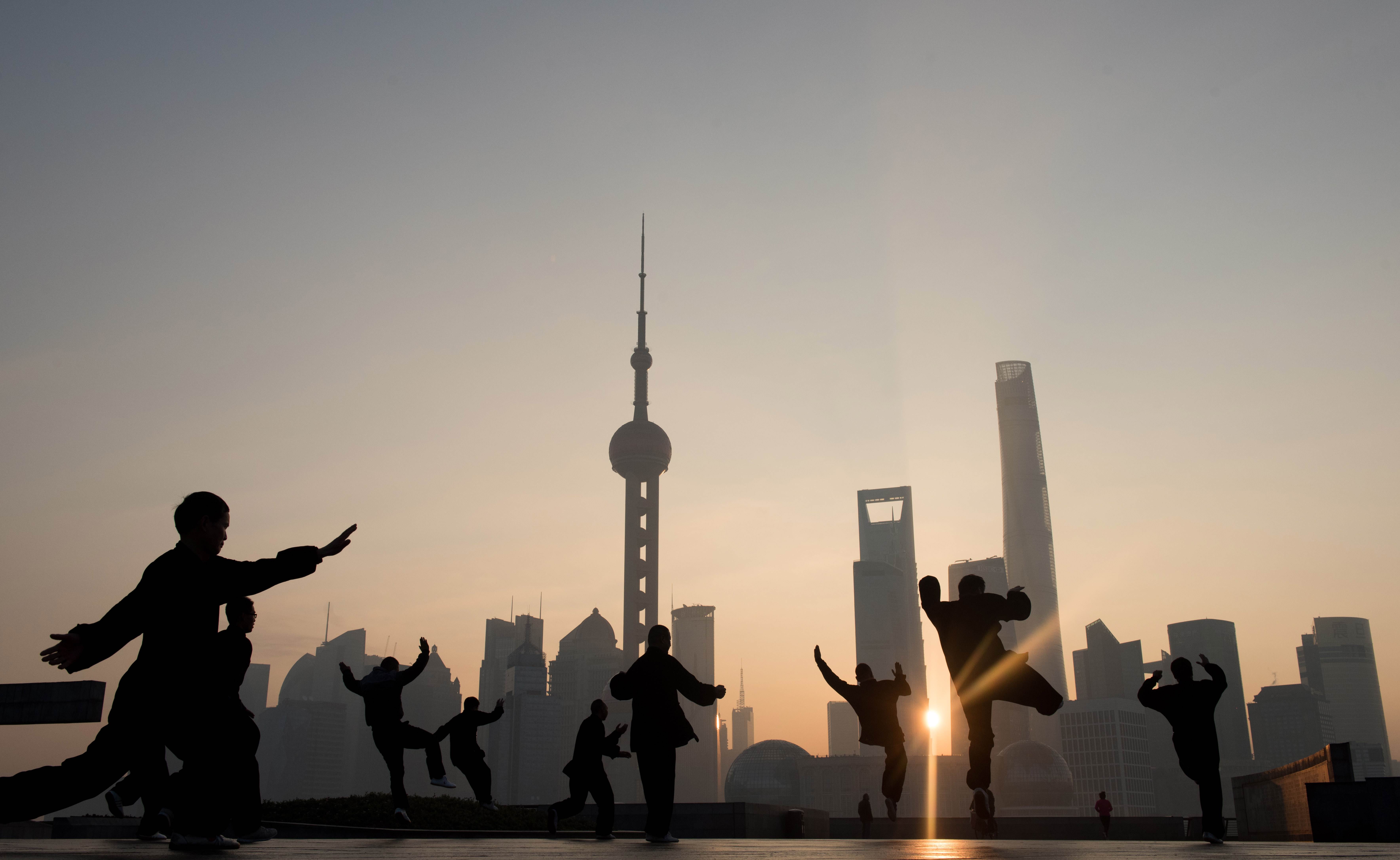 Men do their morning exercises in front of the skyline of the Lujiazui Financial District in Pudong in Shanghai on December 1, 2015. AFP PHOTO / JOHANNES EISELE