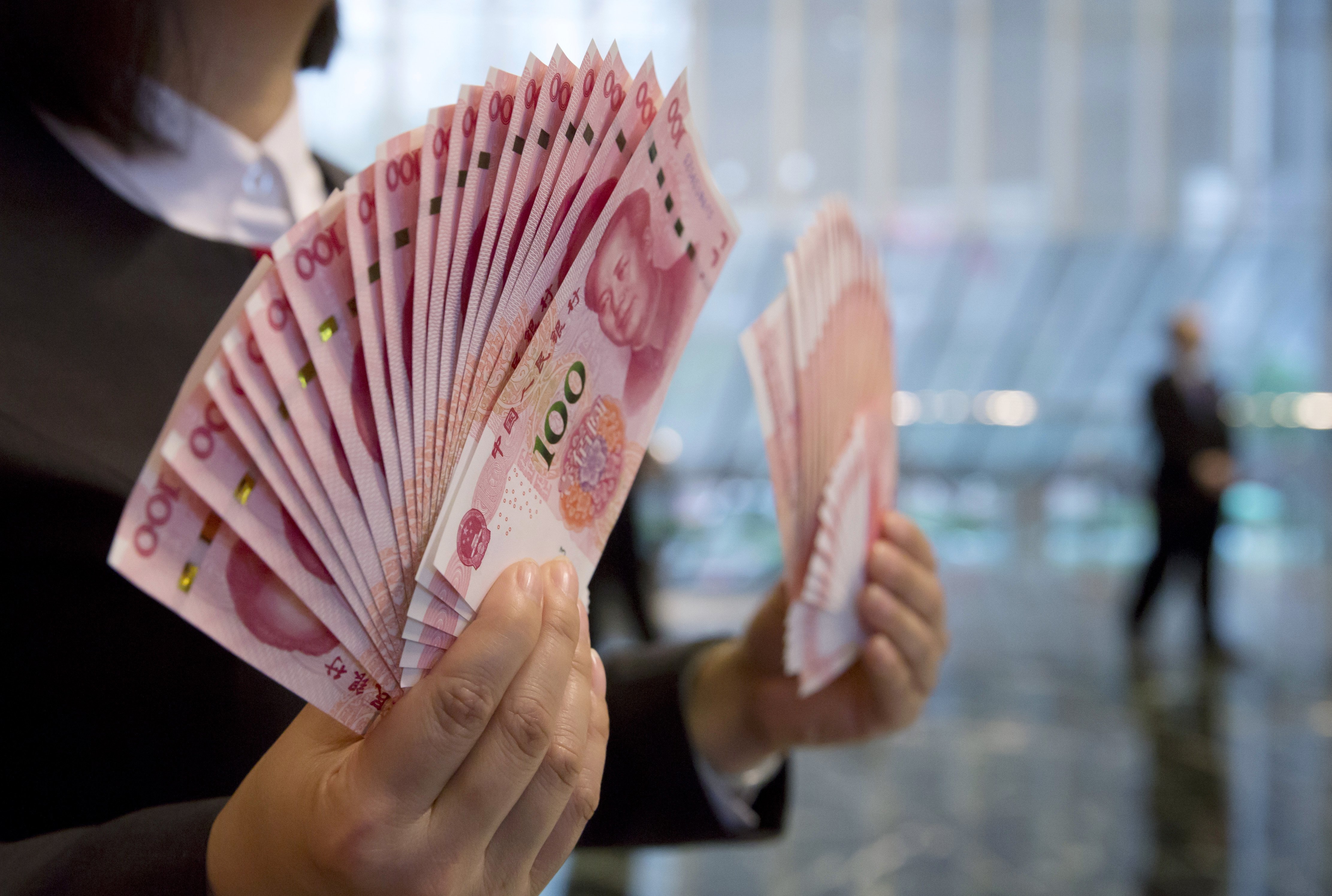 A staff member displays the new version of the 100-yuan RMB banknotes for photographers at the Bank of China Tower in Hong Kong, Thursday, Nov. 12, 2015. China released Thursday a new version of the 100-yuan bill, which bears a golden "100" and adopts advanced anti-counterfeit technology. The "100" on the new bill appears golden from certain angles. (AP Photo/Kin Cheung)