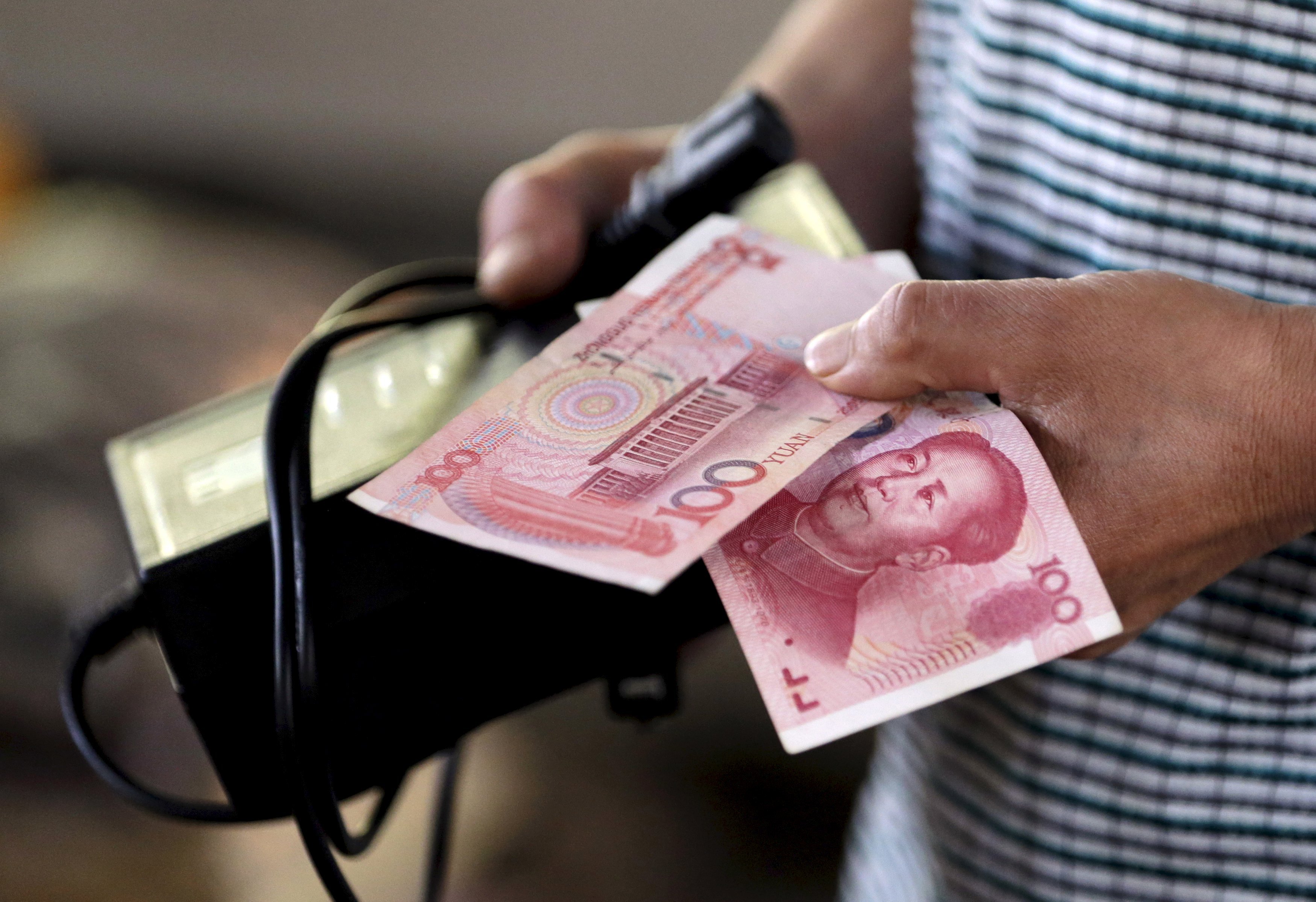 A customer holds a 100 Yuan note at a market in Beijing, in this August 12, 2015, file photo. The International Monetary Fund is expected to add China's yuan to its benchmark currency basket at a board meeting in a symbolic win for Beijing, November 30, 2015. REUTERS/Jason Lee/FilesGLOBAL BUSINESS WEEK AHEAD PACKAGE - SEARCH 'BUSINESS WEEK AHEAD NOVEMBER 30' FOR ALL IMAGES