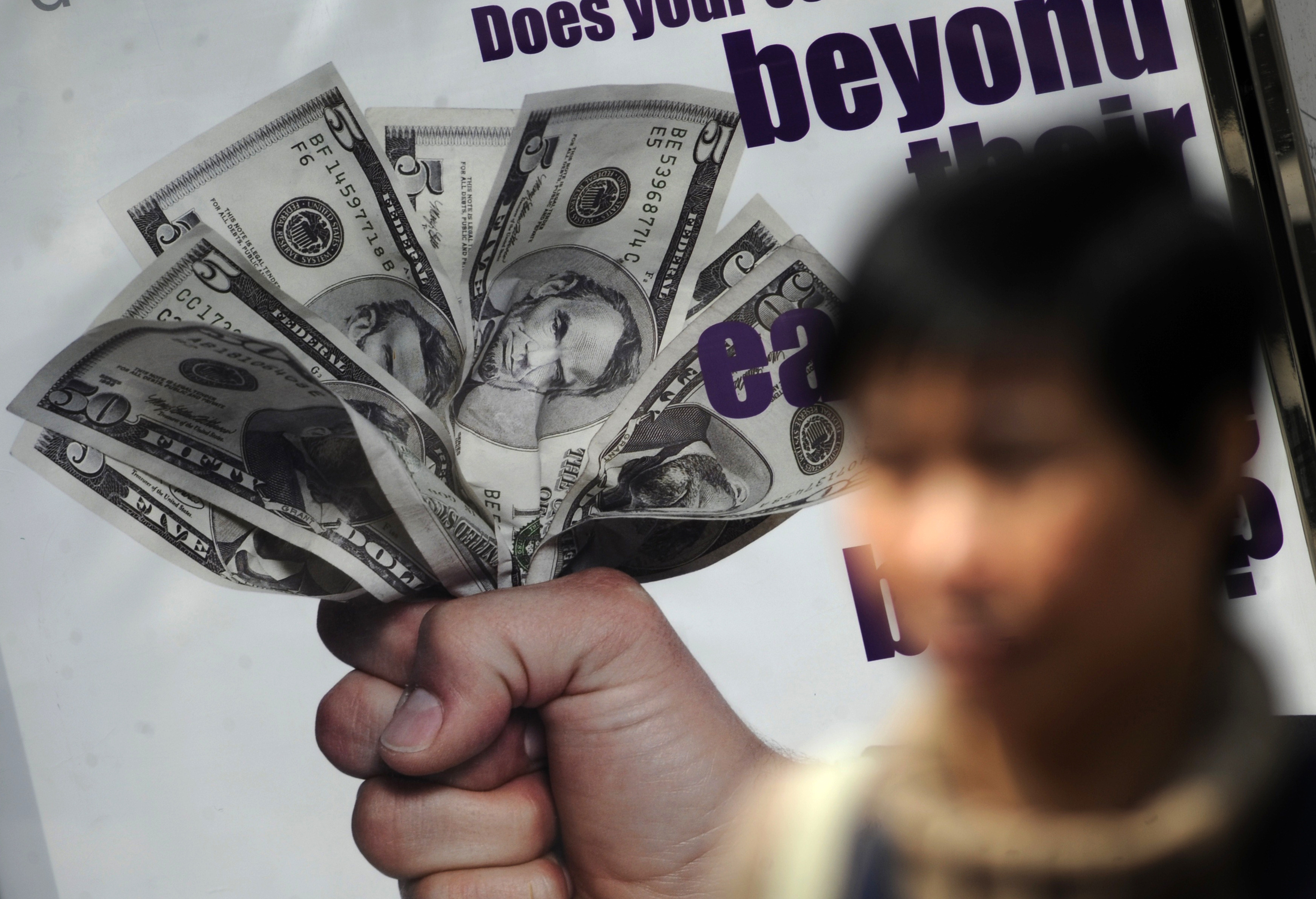 A pedestrian walks past an advertisment featuring US dollar bills in Hong Kong on April 6, 2011. The USD clawed back lost ground against the euro in Asian trade on April 5 following remarks by Fed chief Ben Bernanke that rising US inflation would not persist, analysts said. The greenback rose against most other Asian currencies, strengthening to 43.41 Philippine pesos from 43.32 on April 4, to 1,089.66 South Korean won from 1,087.66 and to 8,658.00 Indonesian rupiah from 8,655.00. AFP PHOTO / Antony DICKSON