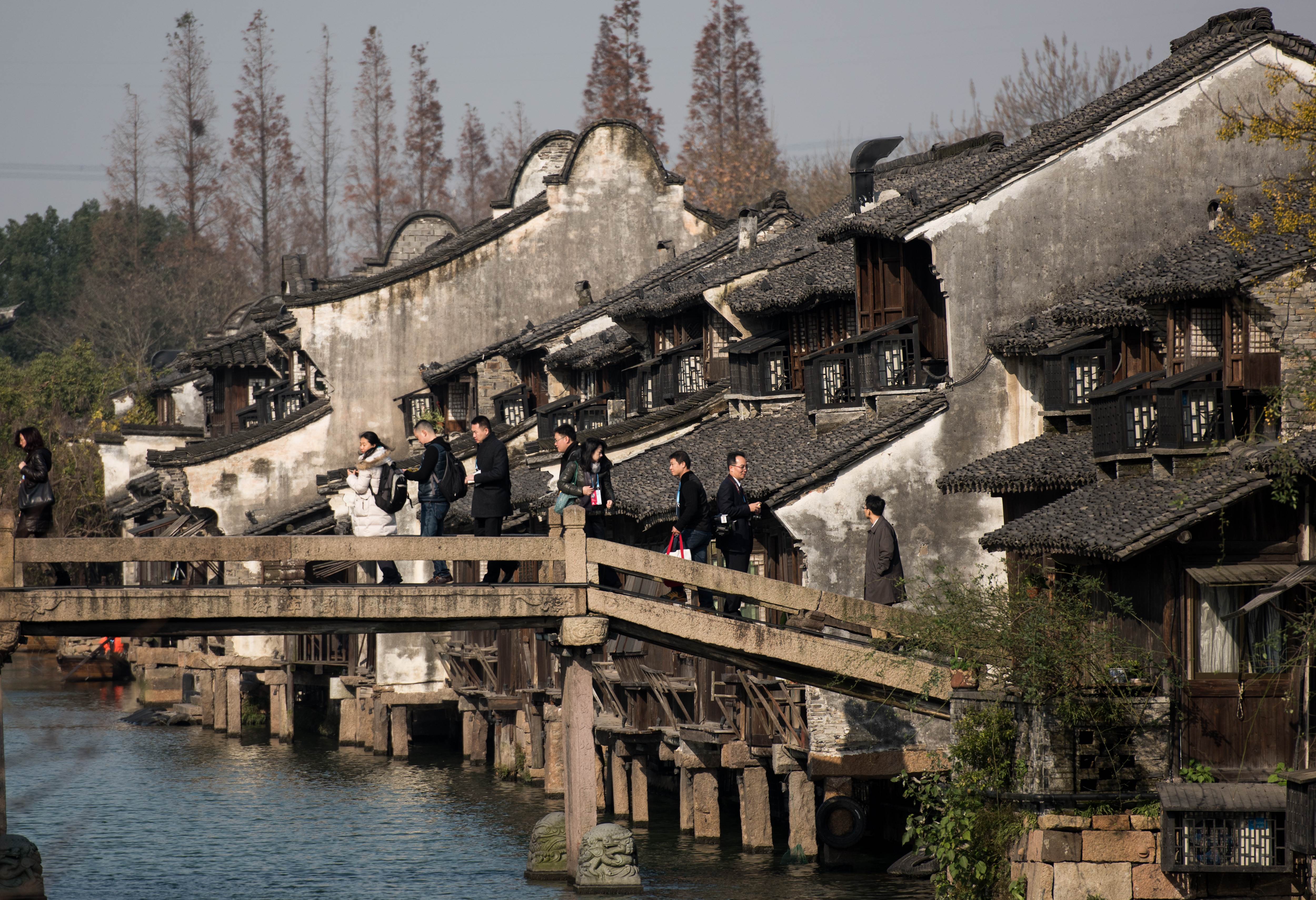 Participants cross a bridge to enter the World Internet Conference venue in the scenic town of Wuzhen in eastern China's Zhejiang province on December 16, 2015. China's second World Internet Conference begins in Wuzhen with officials from technology giants including Nokia, Apple, Kaspersky, IBM and Samsung expected to attend. AFP PHOTO / JOHANNES EISELE