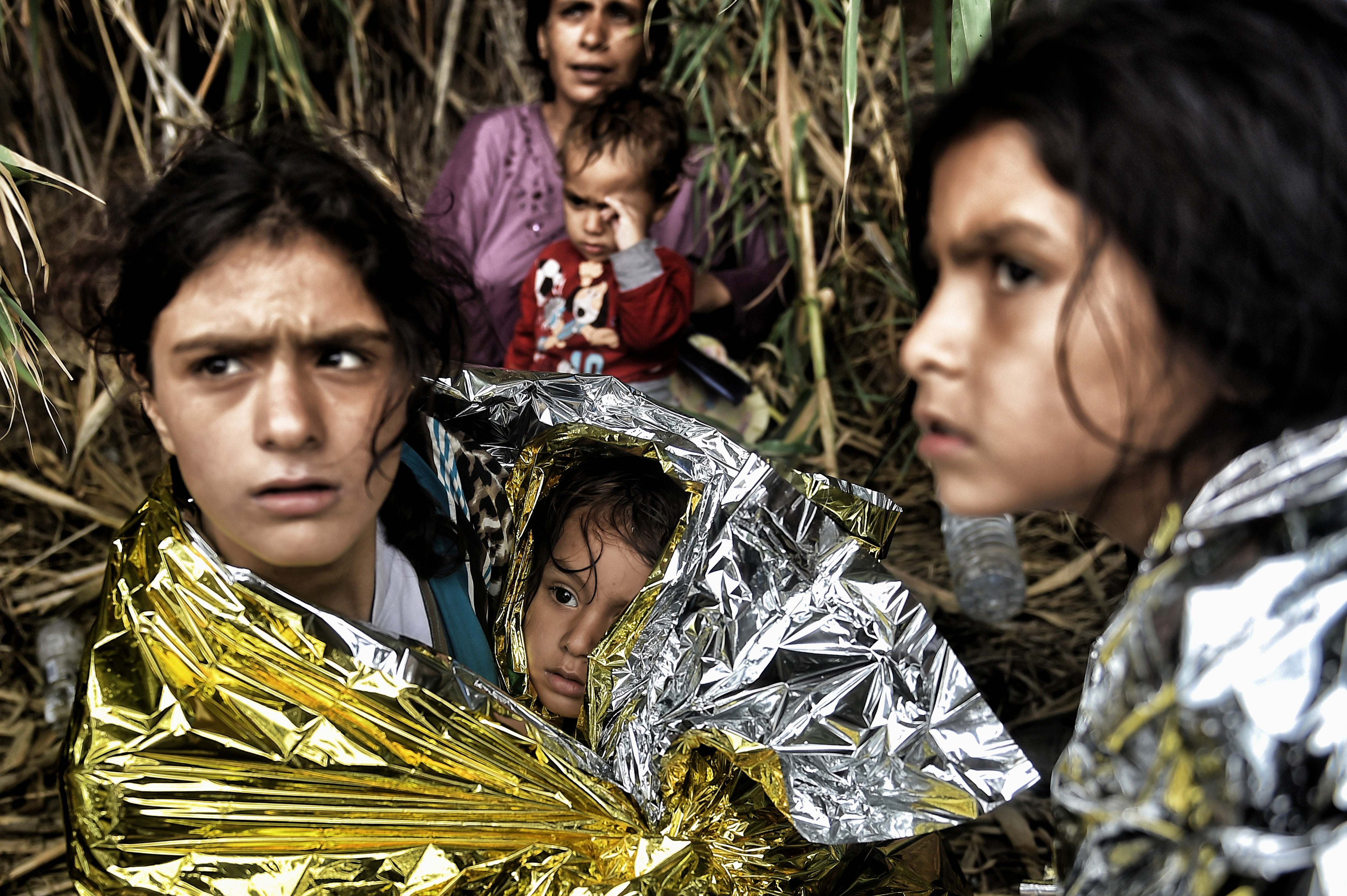 -- AFP PICTURES OF THE YEAR 2015 -- Syrian refugees are covered with life blankets upon arriving to the Greek island of Lesbos, after crossing the Aegean sea from Turkey, on September 28, 2015. Seventeen Syrians including five women and five children trying to reach Greece drowned September 27 when their boat sank in Turkish waters, local media reported. AFP PHOTO / ARIS MESSINIS / AFP / ARIS MESSINIS