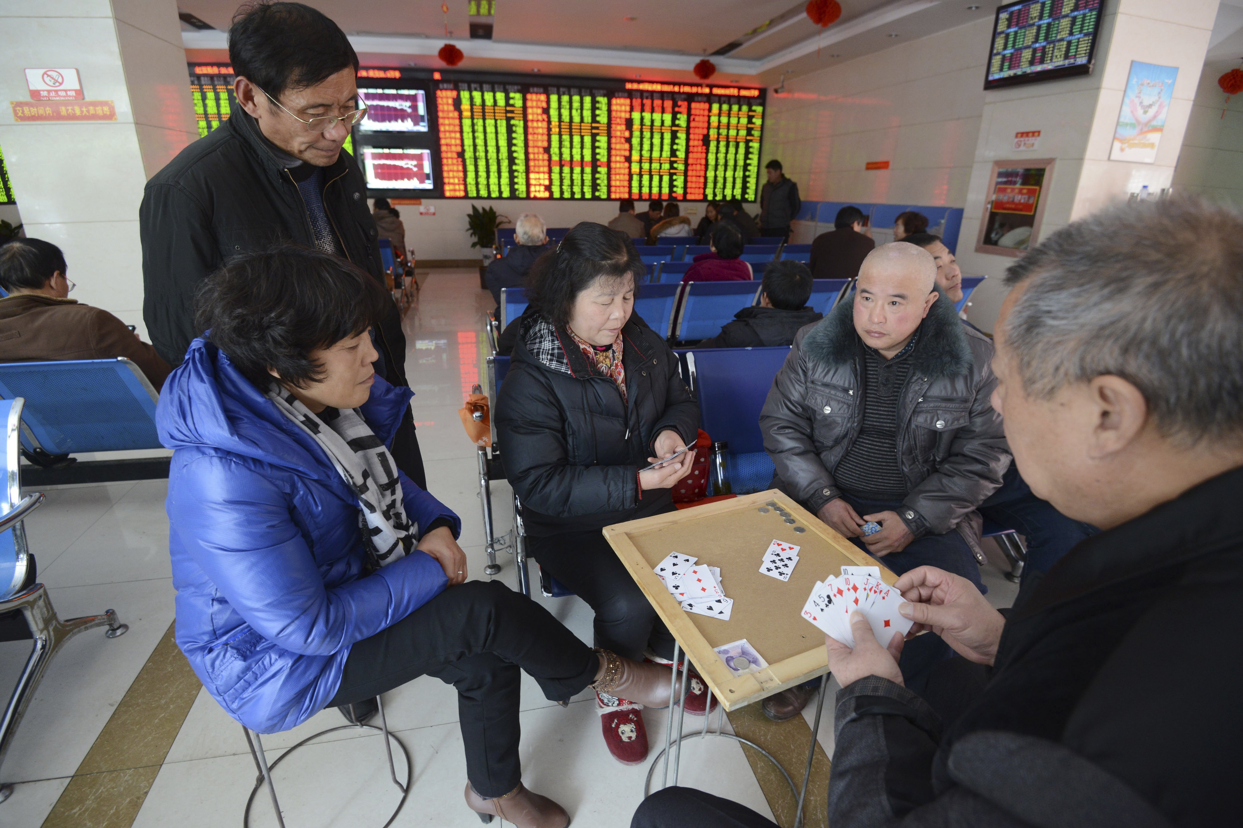 Chinese stock investors play cards at a brokerage house in Fuyang in central China's Anhui province Friday, Nov. 27, 2015. China's stock market fell sharply Friday as investigations into the securities industry widened to include two top brokerages. (Chinatopix via AP) CHINA OUT