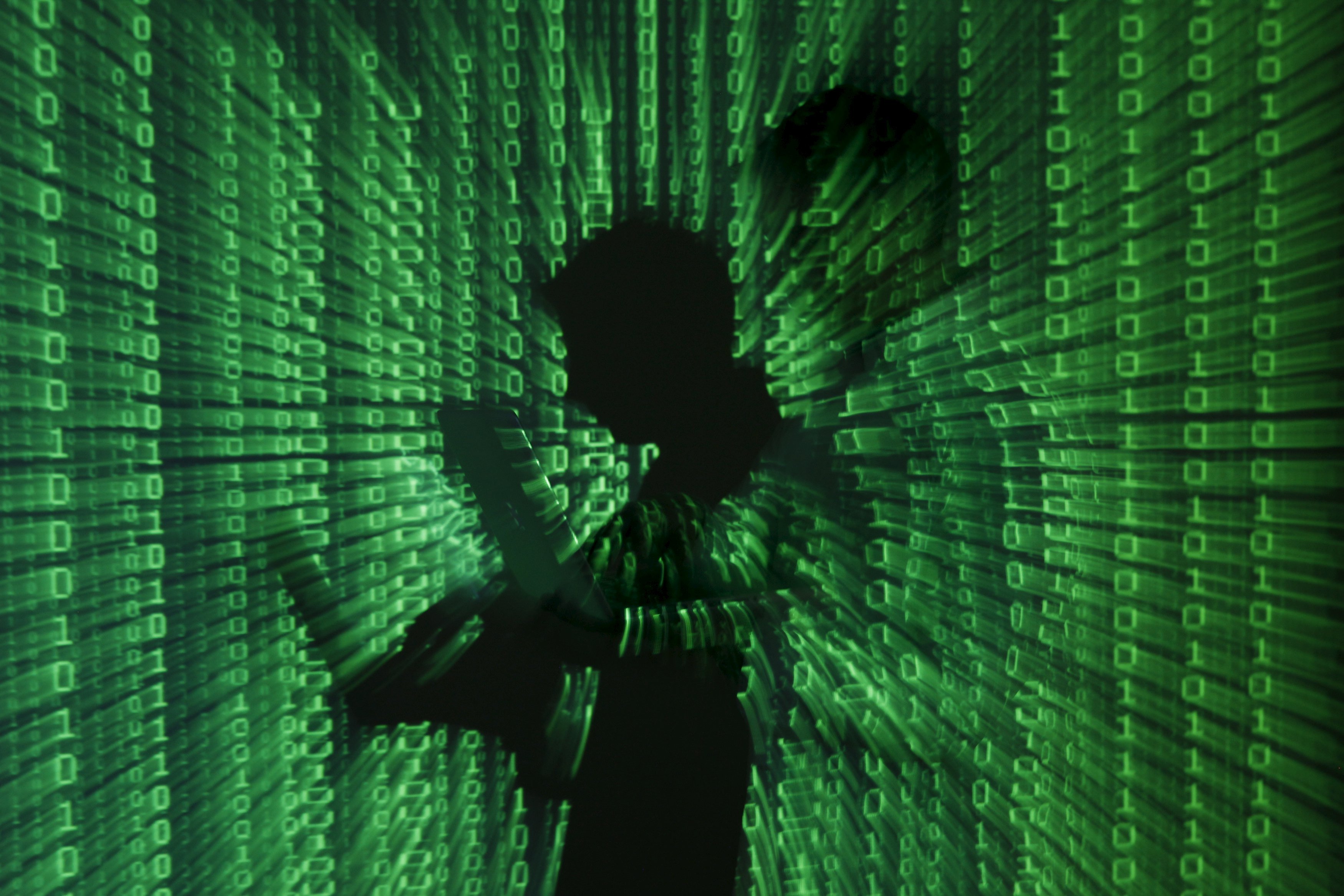 An illustration file picture shows a projection of binary code on a man holding a laptop computer, in an office in Warsaw June 24, 2013. Security researchers have many names for the hacking group that is one of the suspects for the cyberattack on the U.S. government's Office of Personnel Management: PinkPanther, KungFu Kittens, Group 72 and, most famously, Deep Panda. But to Jared Myers and colleagues at cybersecurity company RSA, it is called Shell Crew, and Myers' team is one of the few who has watched it mid-assault — and eventually repulsed it. Myers' account of a months-long battle with the group illustrates the challenges governments and companies face in defending against hackers that researchers believe are linked to the Chinese government - a charge Beijing denies. To match story CYBERSECURITY-USA/DEEP-PANDA REUTERS/Kacper Pempel/Files