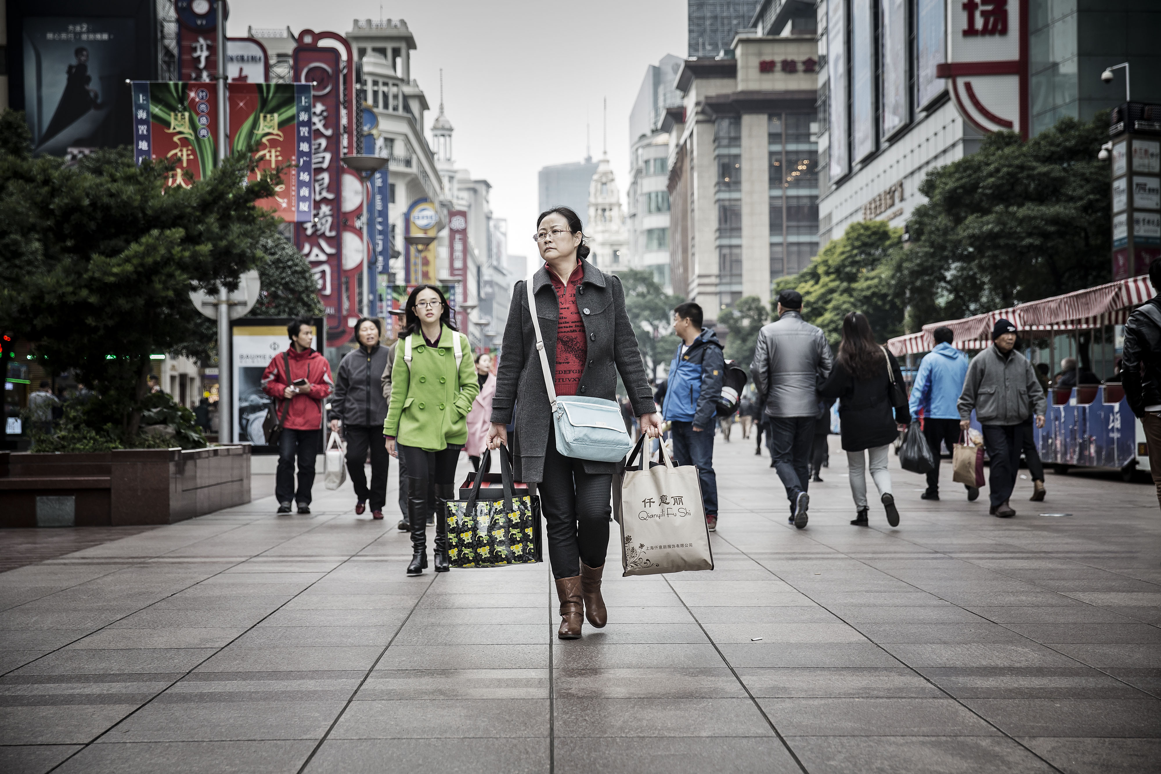 A woman carries shopping bags down Nanjing Road in Shanghai, China, on Saturday, Dec. 5, 2015. Premier Li Keqiang is facing a precarious balancing act as he eases fiscal policy to meet a target of 6.5 percent annual economic growth for the next five years, while reining in a debt pile that is estimated to be already more than twice the size of the world's second-largest economy. Photographer: Qilai Shen/Bloomberg ORG XMIT: 595439177