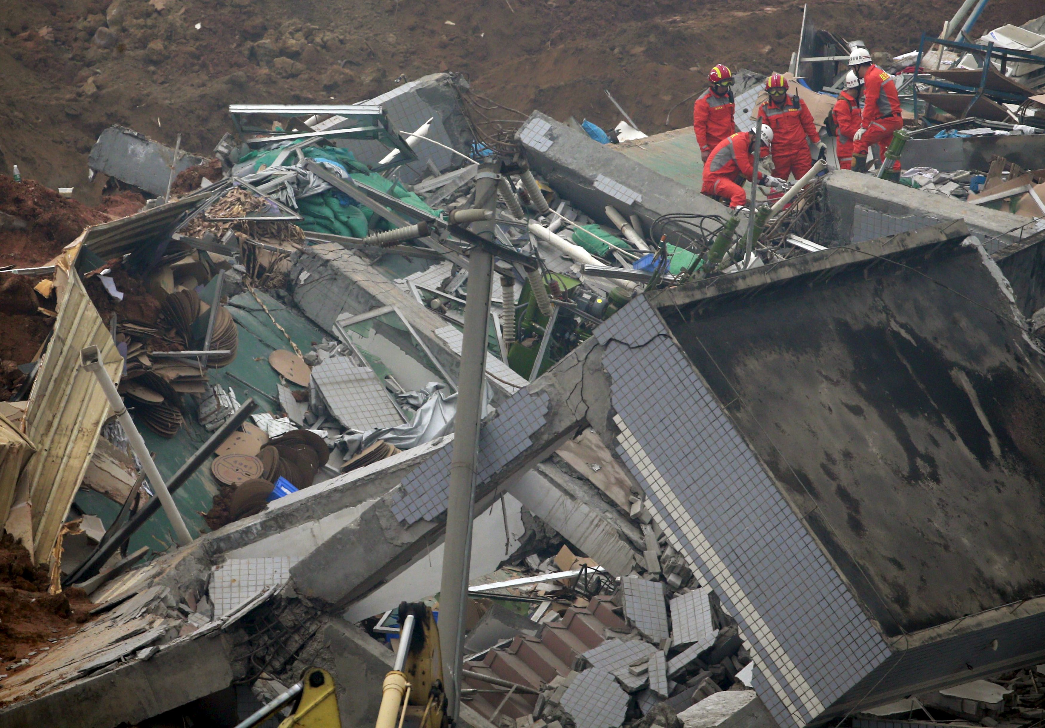 Rescue workers work on a damaged building during search and rescue operations at an industrial estate hit by a landslide in Shenzhen, Guangdong province, December 23, 2015. REUTERS/Kim Kyung-Hoon