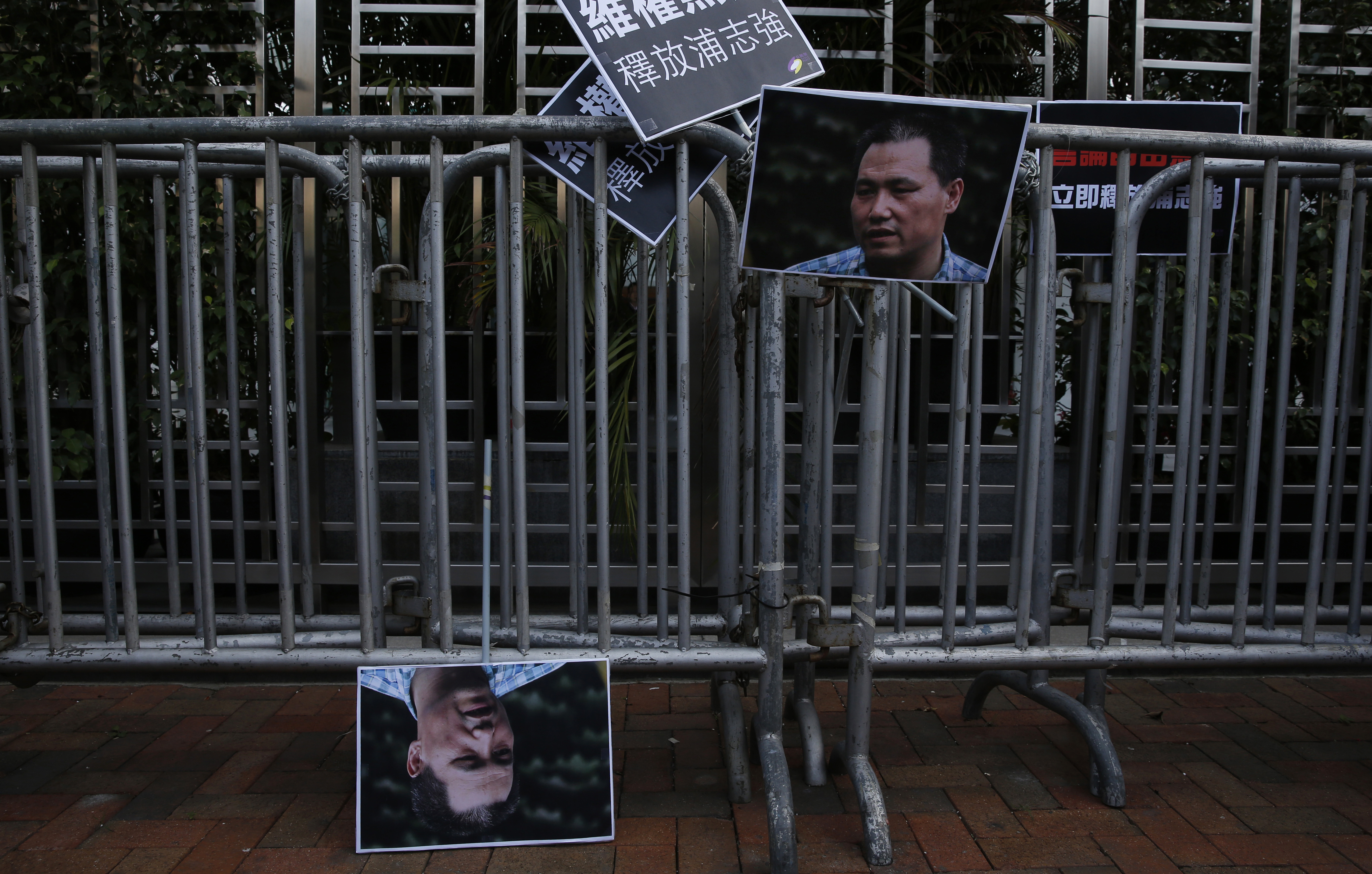 Pictures of human rights lawyer Pu Zhiqiang are displayed by anti-Beijing protesters, outside the Chinese liaison office to demand Pu's release, in Hong Kong, Tuesday, Dec. 15, 2015. Pu, a prominent rights lawyer stood trial on charges of provoking trouble and stirring ethnic hatred with online commentary critical of the ruling Communist Party at a Beijing court on Monday. Placards read "Release Pu Zhiqiang." (AP Photo/Kin Cheung)