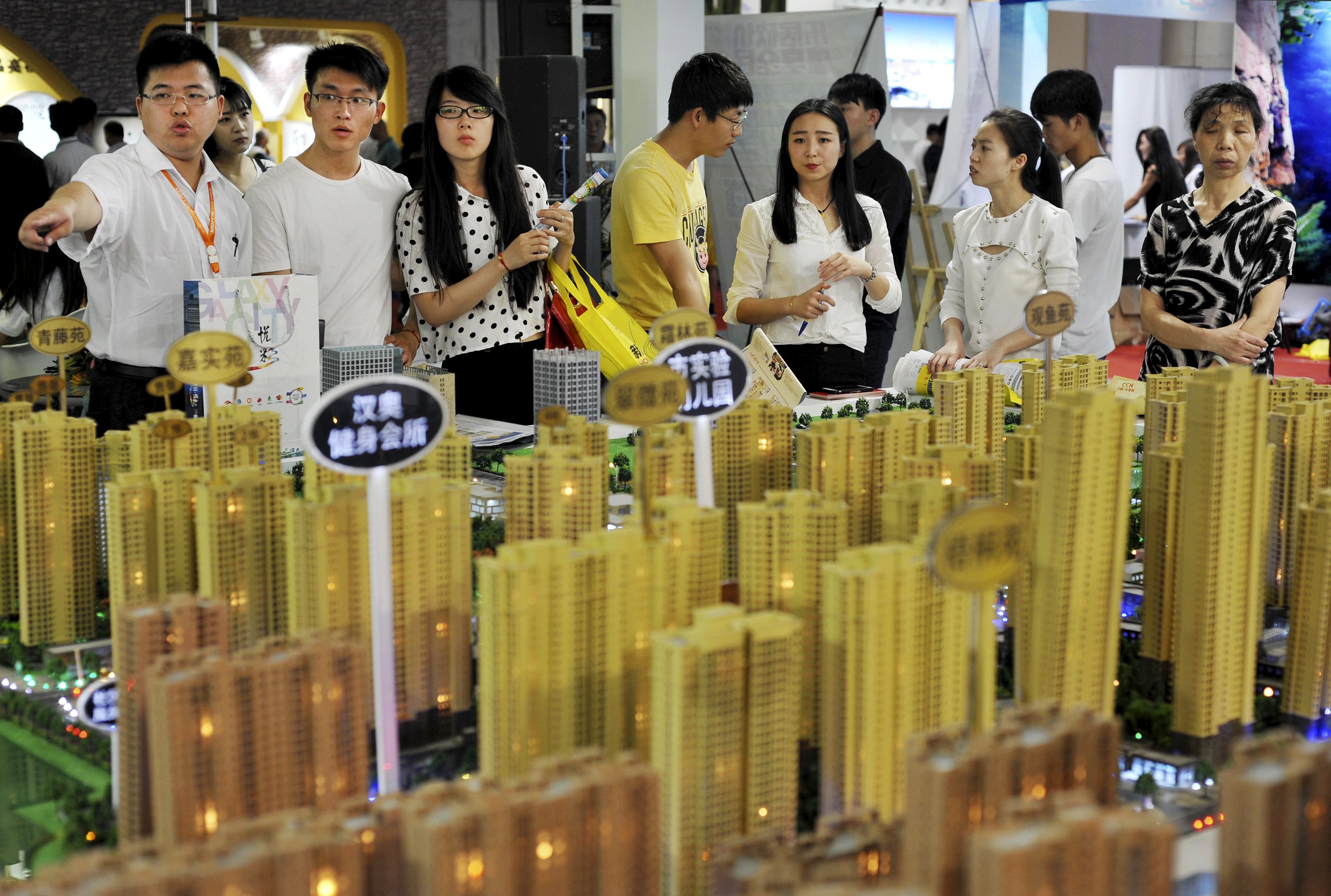 Sales representatives talk to potential buyers in front of a model of a residential complex at a real estate exhibition in Wuhan, Hubei province, China, May 10, 2015. Executives at nearly a dozen listed Chinese developers say they will ramp up investment in property this year thanks to Beijing's interest rate cuts, a vote of confidence from a sector accounting for 15 percent of economic growth. Picture taken May 10, 2015. REUTERS/Stringer CHINA OUT. NO COMMERCIAL OR EDITORIAL SALES IN CHINA
