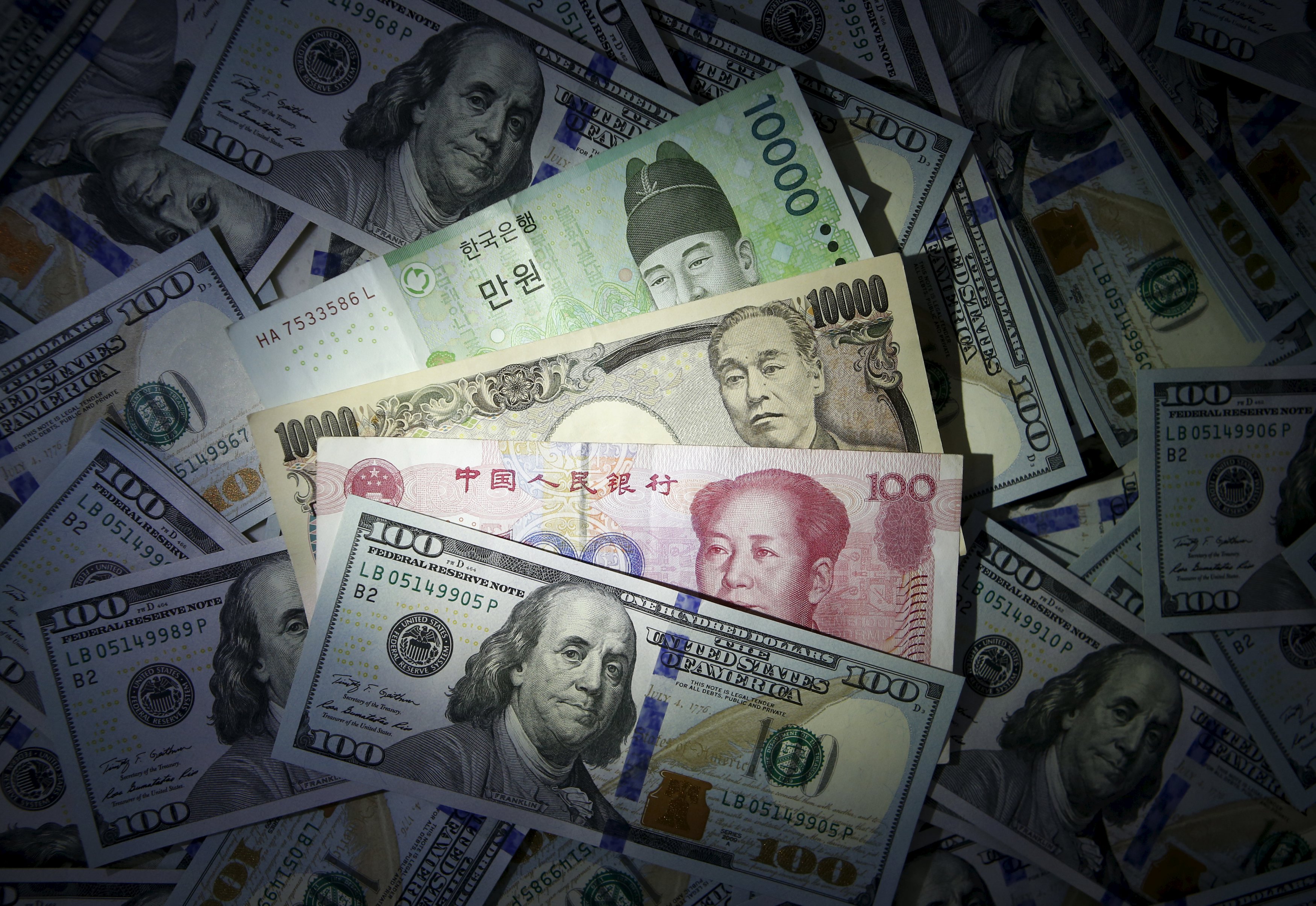 South Korean won, Chinese yuan and Japanese yen notes are seen on U.S. 100 dollar notes in this picture illustration taken in Seoul, South Korea, December 15, 2015. As investors brace for this week's historic U.S. interest rate decision, central banks in Asia's emerging markets will be standing by a quarter of a trillion dollars in emergency liquidity lines with China and Japan to prevent routs in their currencies. REUTERS/Kim Hong-Ji