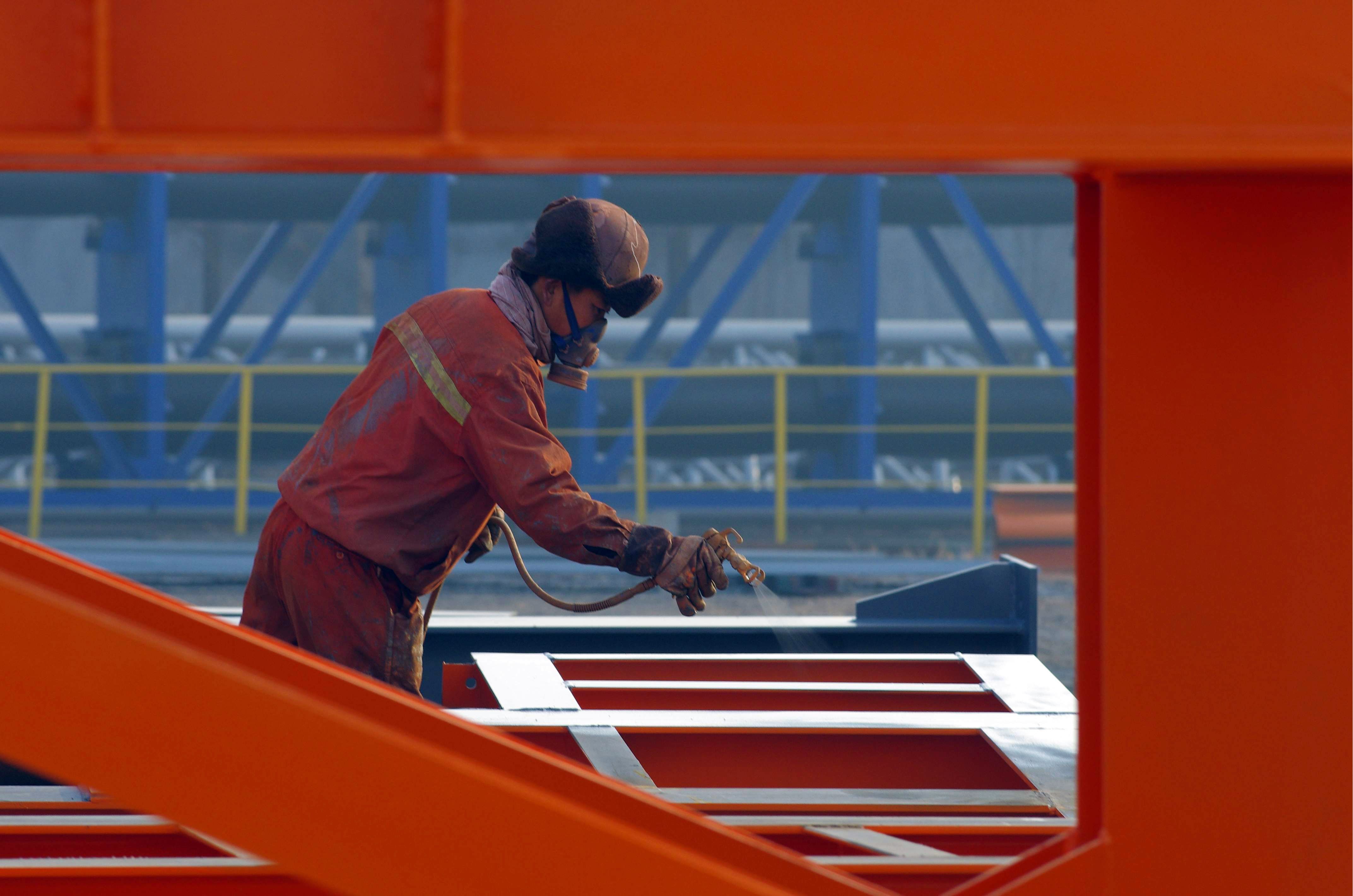 This picture taken on January 2, 2016 shows a Chinese worker spraying lacquer on steel in a factory in Rizhao, east China's Shandong province. China's factory activity shrank further in December, a private survey showed on January 4, the 10th consecutive month of contraction with the world's second-largest economy set to post its weakest growth in a quarter of a century. CHINA OUT AFP PHOTO