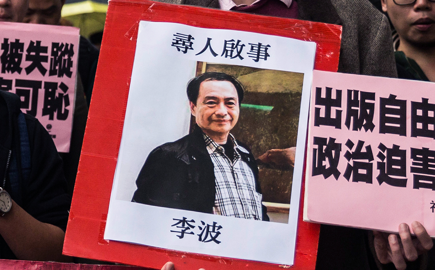 In this picture taken on January 3, 2016, a protestor holds up a missing person notice for Lee Bo, 65, the latest of five Hong Kong booksellers from the same Mighty Current publishing house to go missing, as they walk towards China's Liaison Office in Hong Kong. Britain confirmed on January 5 that one of five missing Hong Kong booksellers feared detained by Chinese authorities is a UK citizen, saying it was "deeply concerned" over the disappearances. AFP PHOTO / ANTHONY WALLACE