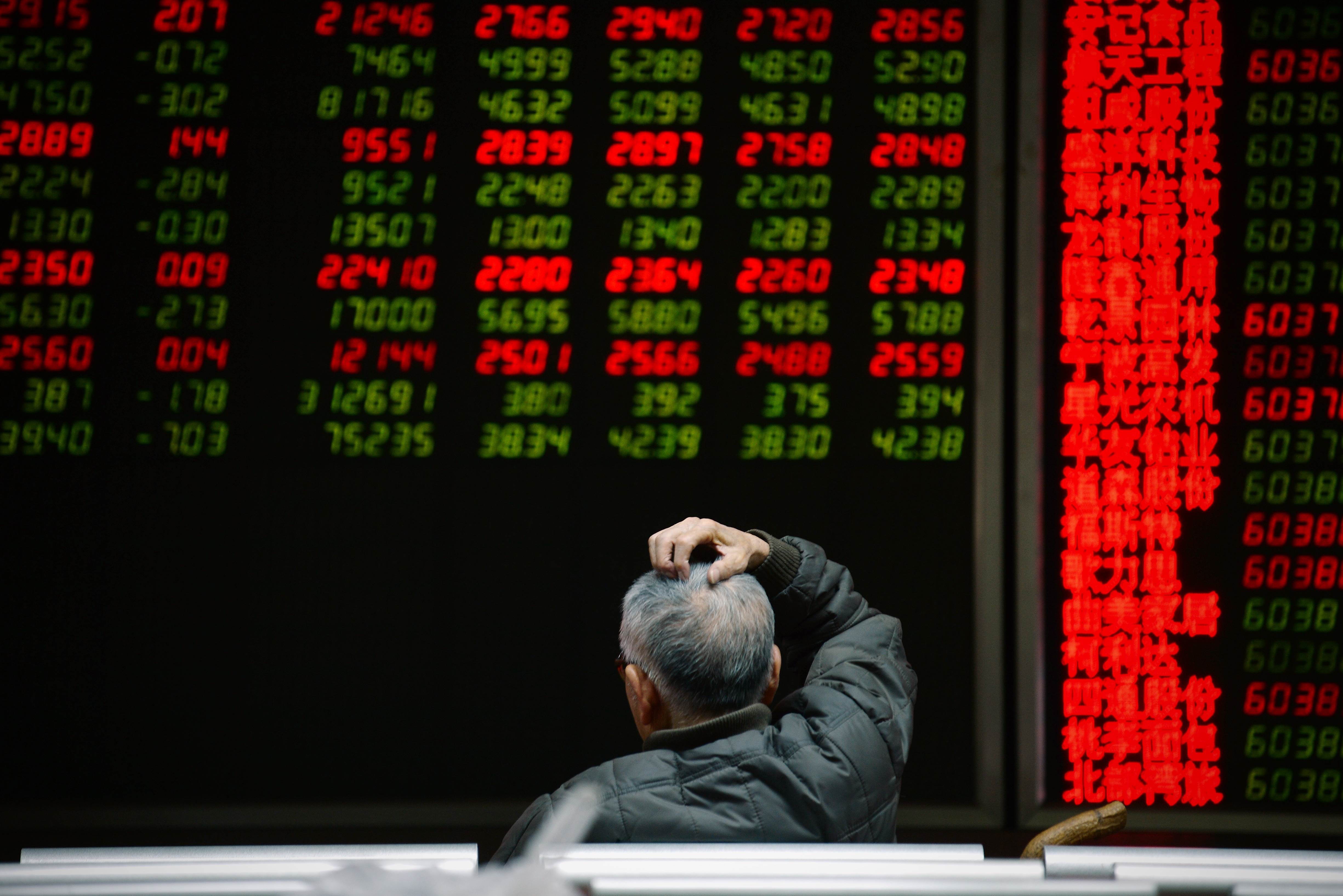 An investor looks at screens showing stock market movements at a securities company in Beijing on January 14, 2016. Shanghai stocks gave up early gains on January 13 to end the morning flat despite a better-than-expected trade report out of China, but Hong Kong rallied. AFP PHOTO / WANG ZHAO