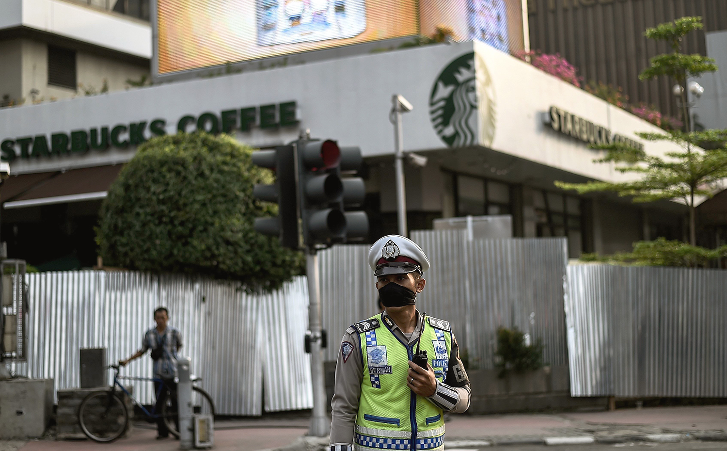 An Indonesian policeman stands guard in front of the damaged Starbucks building in Jakarta on January 15, 2016, a day after a series of explosions hit the Indonesian capital. Islamic State suicide bombers and gunmen struck the capital of Muslim-majority Indonesia on January 14, executing a Westerner and blowing up a Starbucks in an assault police said bore the hallmarks of the Paris attacks. AFP PHOTO / MANAN VATSYAYANA