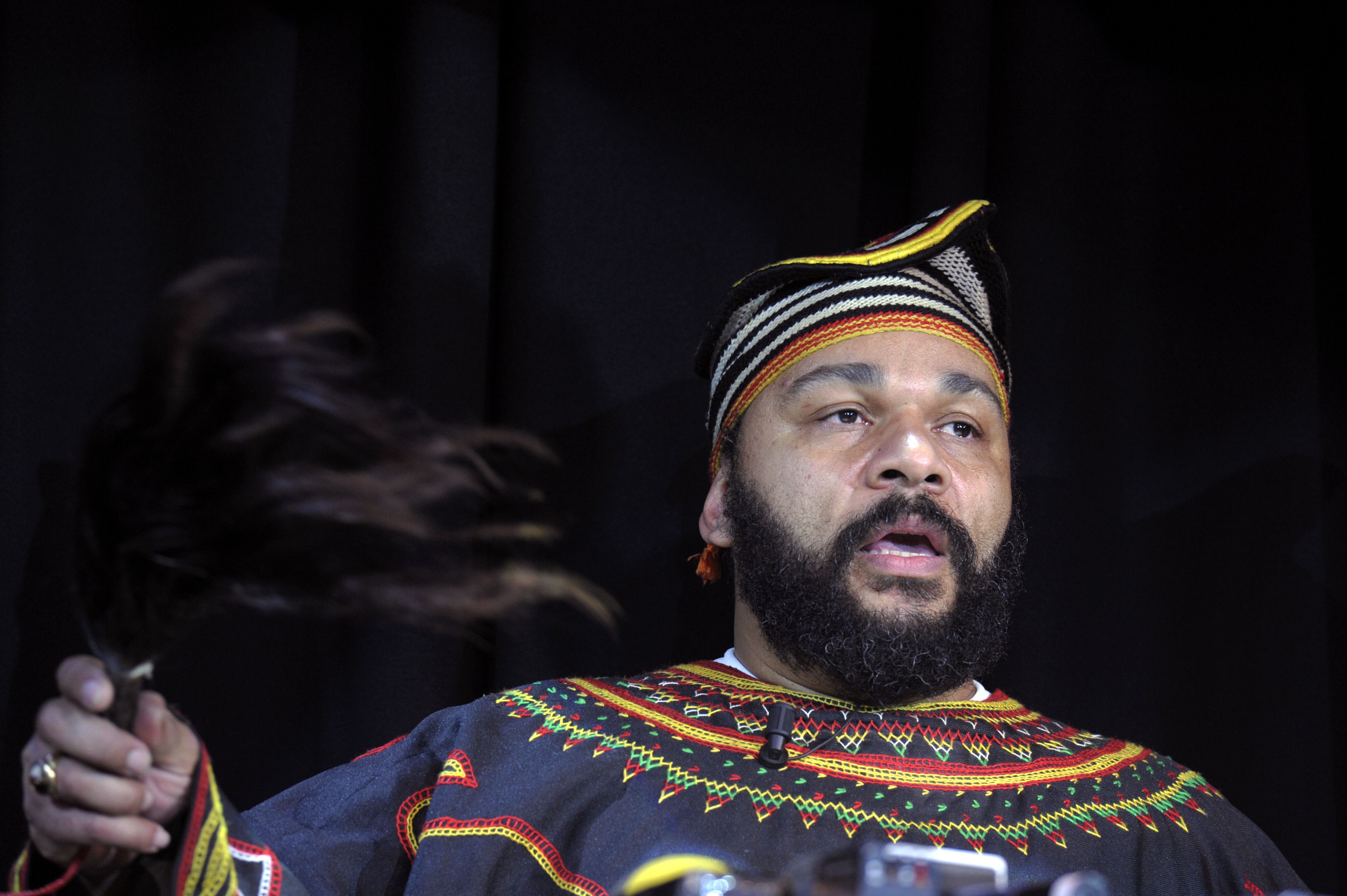 (FILES) In this file picture taken on January 11, 2014 controversial French humourist Dieudonne M'bala M'bala holds a fly-swat as he gives a press conference in the Theatre de la Main d'or in Paris. Controversial French comedian Dieudonne M'bala M'bala has been banned from entering Britain, the interior ministry said on February 3, 2014, after he reportedly planned to visit to support Nicolas Anelka over the footballer's use of the "quenelle" gesture. "We can confirm that Mr Dieudonne is subject to an exclusion order. The home secretary will seek to exclude an individual from the UK if she considers that there are public policy or public security reasons to do so," a Home Office spokeswoman said. AFP PHOTO / ALAIN JOCARD