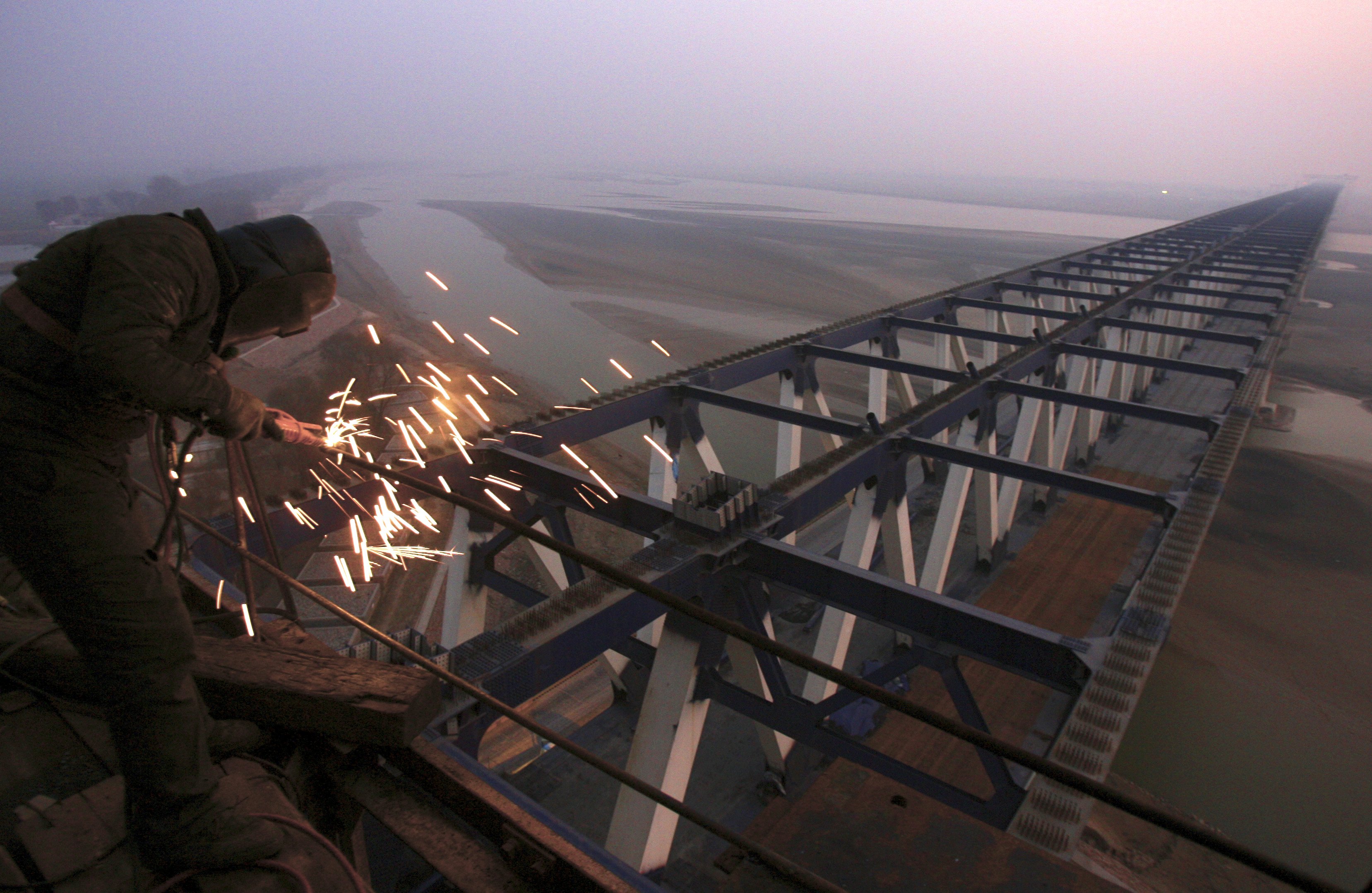 A worker welds steel frames at a construction site of a railway bridge in Zhengzhou, Henan province in this December 17, 2009 file photo. China is expected to release GDP data this week. REUTERS/Donald Chan/Files GLOBAL BUSINESS WEEK AHEAD PACKAGE - SEARCH "BUSINESS WEEK AHEAD JANUARY 18" FOR ALL IMAGES