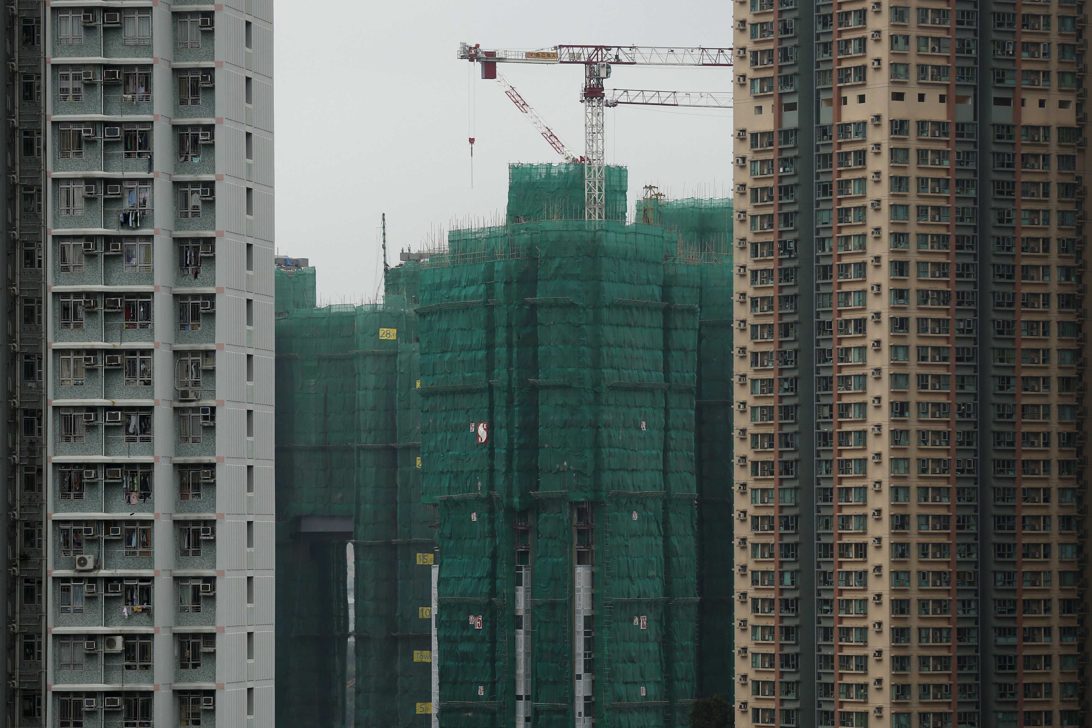 Construction cranes are seen at the building site of a new private housing complex in Hong Kong, China December 15, 2015. Hong Kong is bracing for greater economic challenges as the prospect of a new cycle of interest rate rises drives fears of capital outflows that could put further pressure on the Asian financial hub. Hong Kong's property market, which has seen prices more than double since 2008, had already slowed in anticipation of a local rate hike, and analysts say a further slowdown will depend on China, which is facing its weakest growth in 25 years. Picture taken December 15. REUTERS/Tyrone Siu