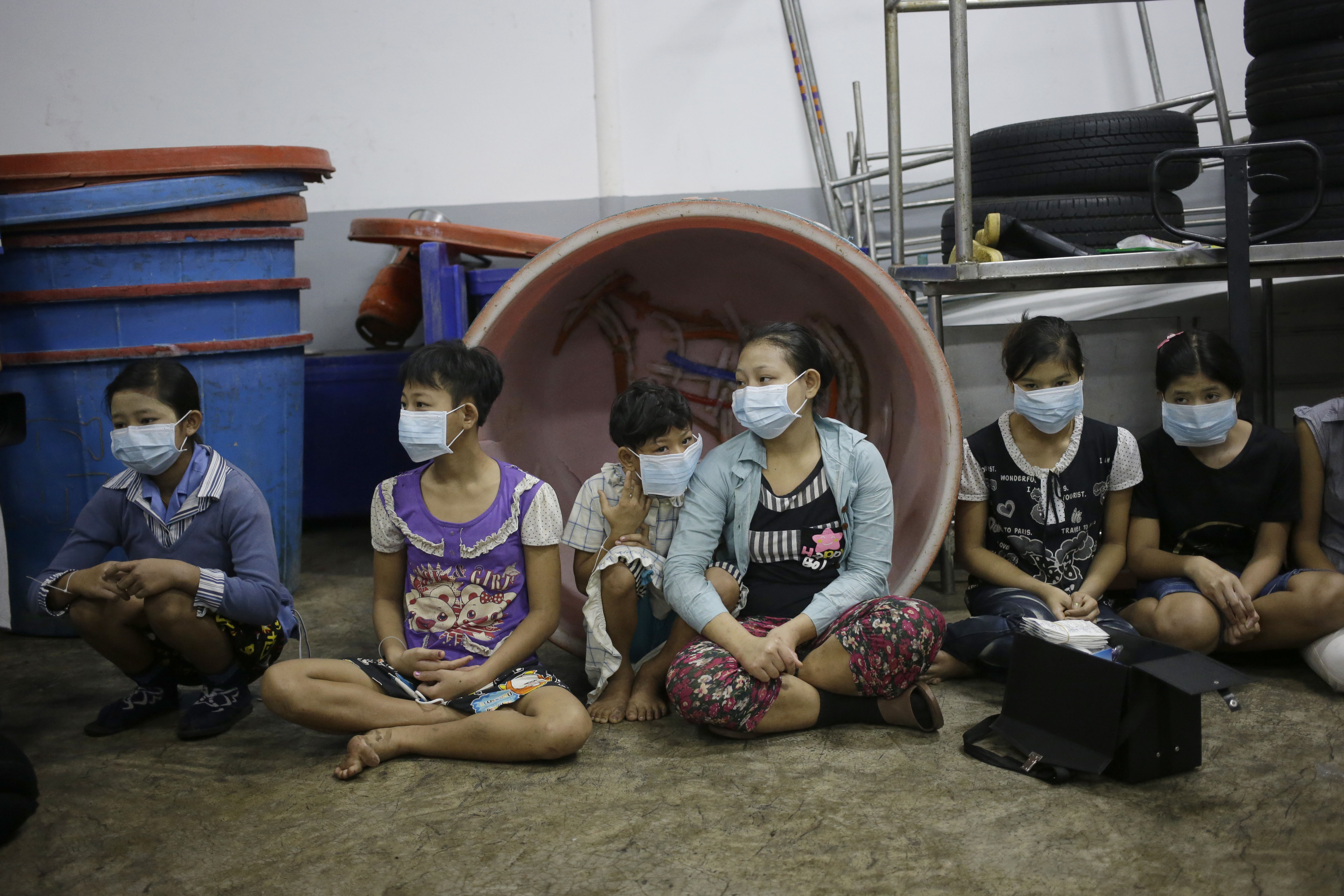 ADVANCE FOR USE MONDAY, DEC. 14, 2015 AT 12:01 A.M. EST (05:01 GMT) AND THEREAFTER - In this Monday, Nov. 9, 2015 photo, children sit together to be registered by officials during a raid on a shrimp shed in Samut Sakhon, Thailand. Abuse is common in Samut Sakhon, which attracts workers from some of the world’s poorest countries, mostly from Myanmar. An International Labor Organization report estimated 10,000 migrant children aged 13 to 15 work in the city. Another U.N. agency study found nearly 60 percent of Burmese laborers toiling in its seafood processing industry were victims of forced labor. (AP Photo/Dita Alangkara)