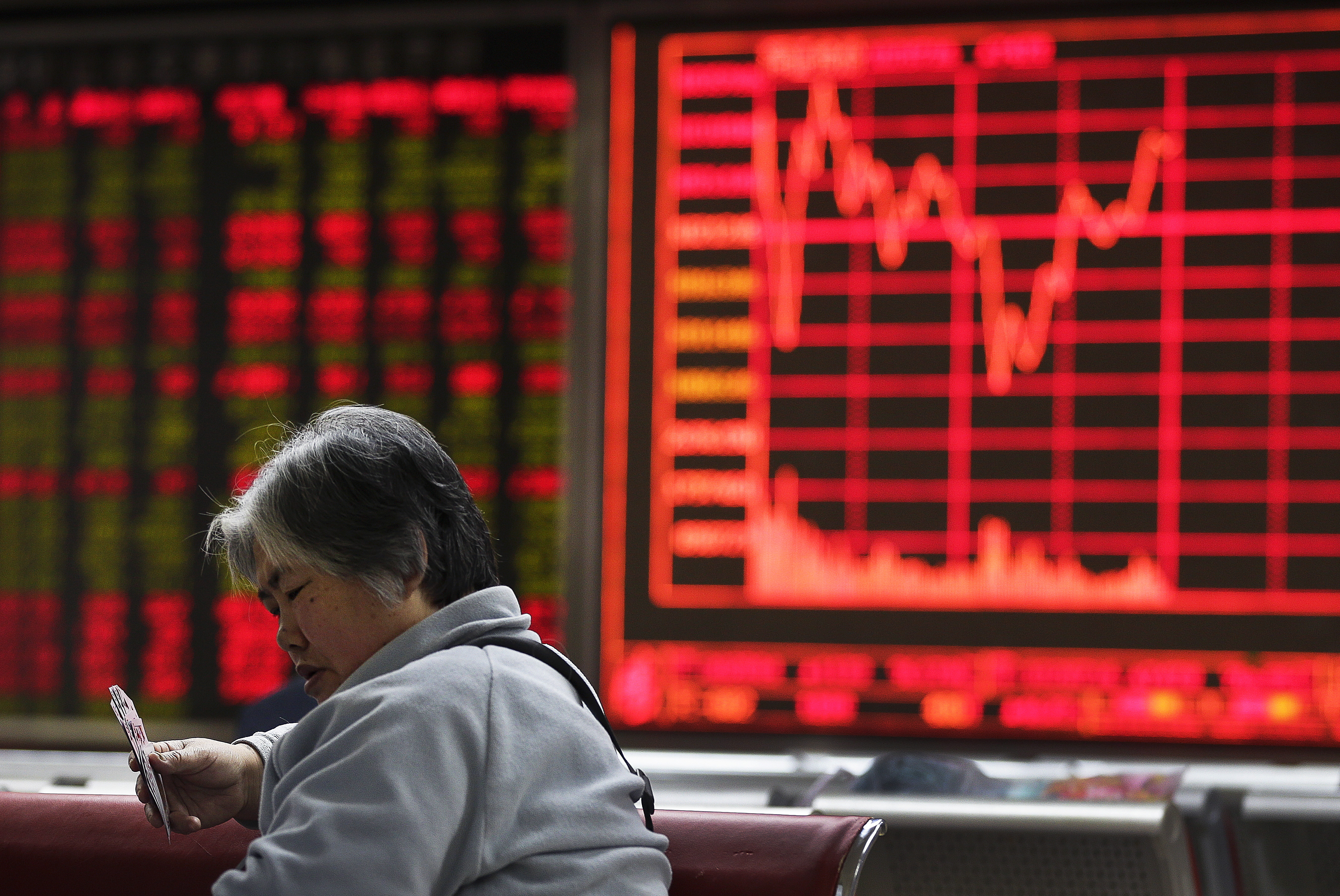 A woman plays cards with other investors at a brokerage house in Beijing, Tuesday, Jan. 12, 2016. Chinese stocks seesawed Tuesday as worries lingered over the country's financial markets and economic outlook, fueling volatility in other Asian benchmarks. (AP Photo/Andy Wong)