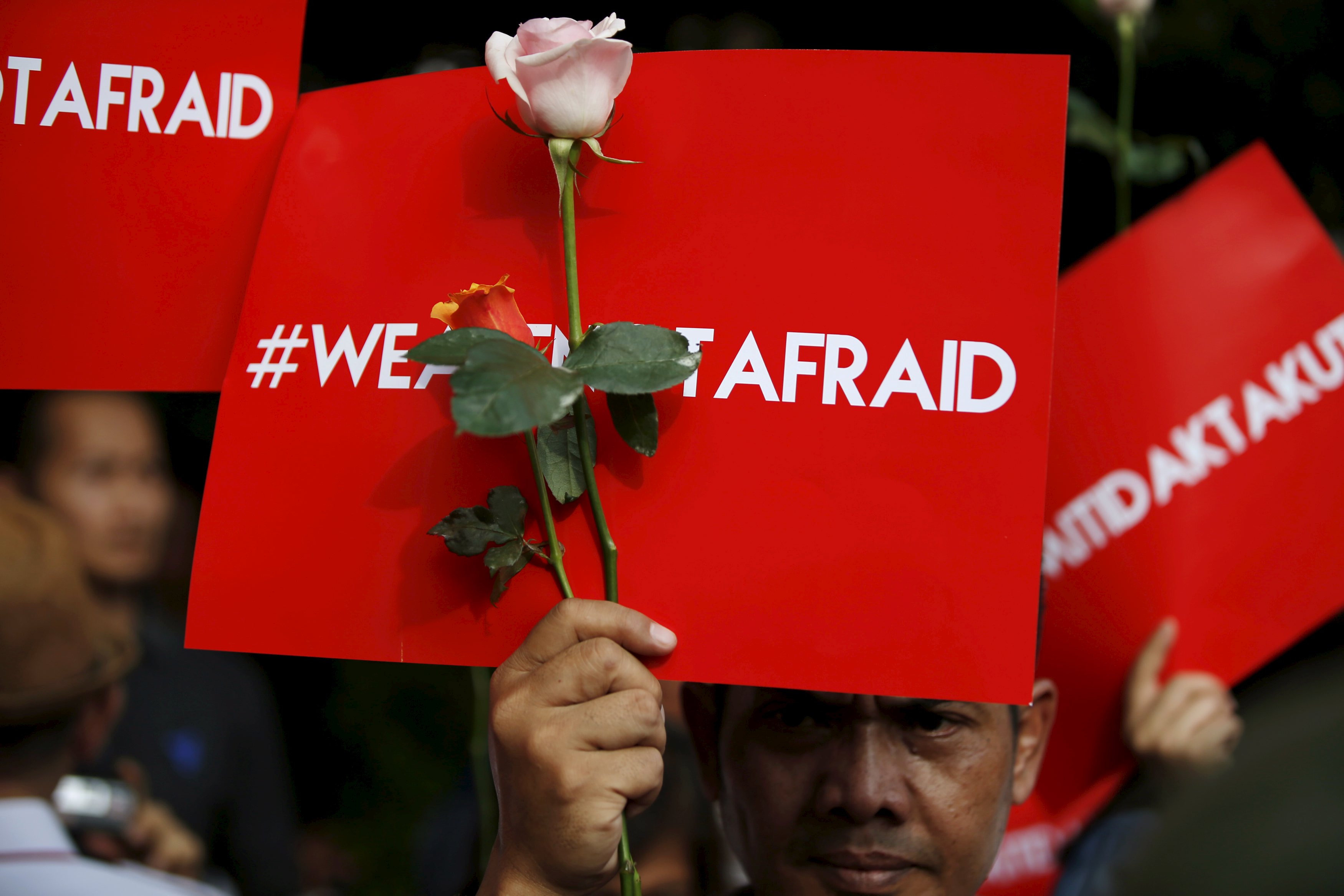 People hold placards reading "We are not afraid" during a rally at the scene of Thursday's gun and bomb attack in central Jakarta, Indonesia January 15, 2016. Indonesian police arrested three suspected militants in a pre-dawn raid and hunted down others across the country on Friday, a day after an attack by Islamic State suicide bombers and gunmen in the heart of the Southeast Asian nation's capital. REUTERS/Darren Whiteside