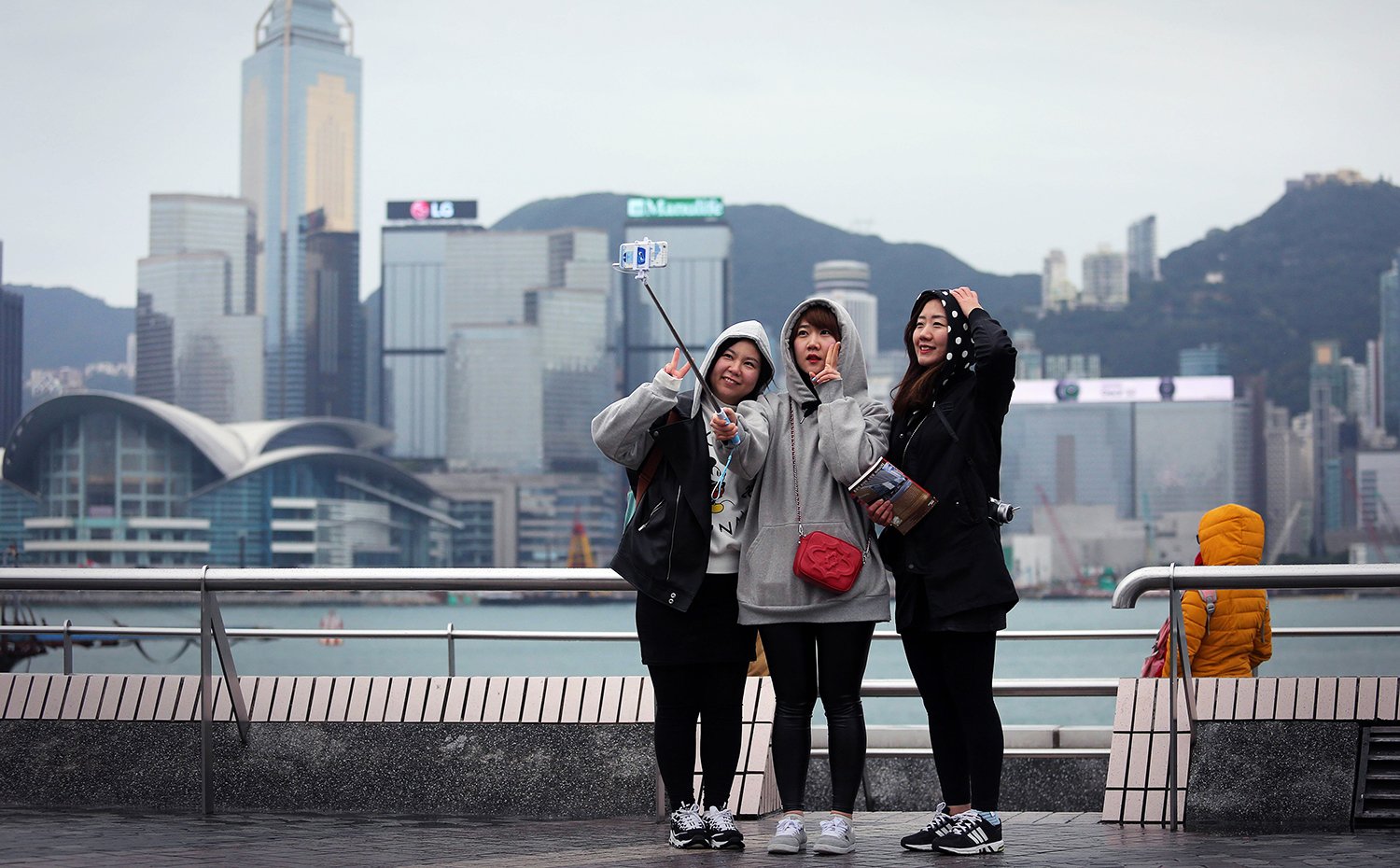 Three girls take a selfie as they brave the cold on a viewing deck next to Victoria Harbour in the Tsim Sha Tsui district of Hong Kong on January 24, 2016. A cold snap gripped Hong Kong on January 24, with residents shivering as temperatures plunged to the lowest point in nearly 60 years and frost dusted the mountaintops of a city accustomed to a subtropical climate. AFP PHOTO / ISAAC LAWRENCE