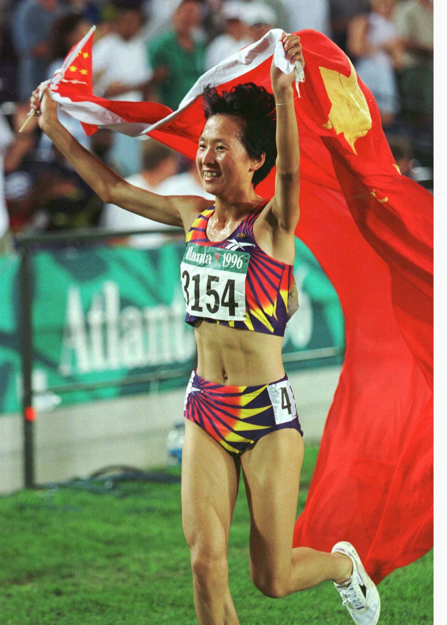 OSP61:OLYMPICS-ATHLETICS: ATLANTA, GA, 28 JUL 96 - Wang Junxia of China celebrates with her country's flag after winning the women's 5000 meter event to earn the Gold medal July 28 at the Olympic stadium in Atlanta. fsp/Photo by Jerry Lampen REUTERS