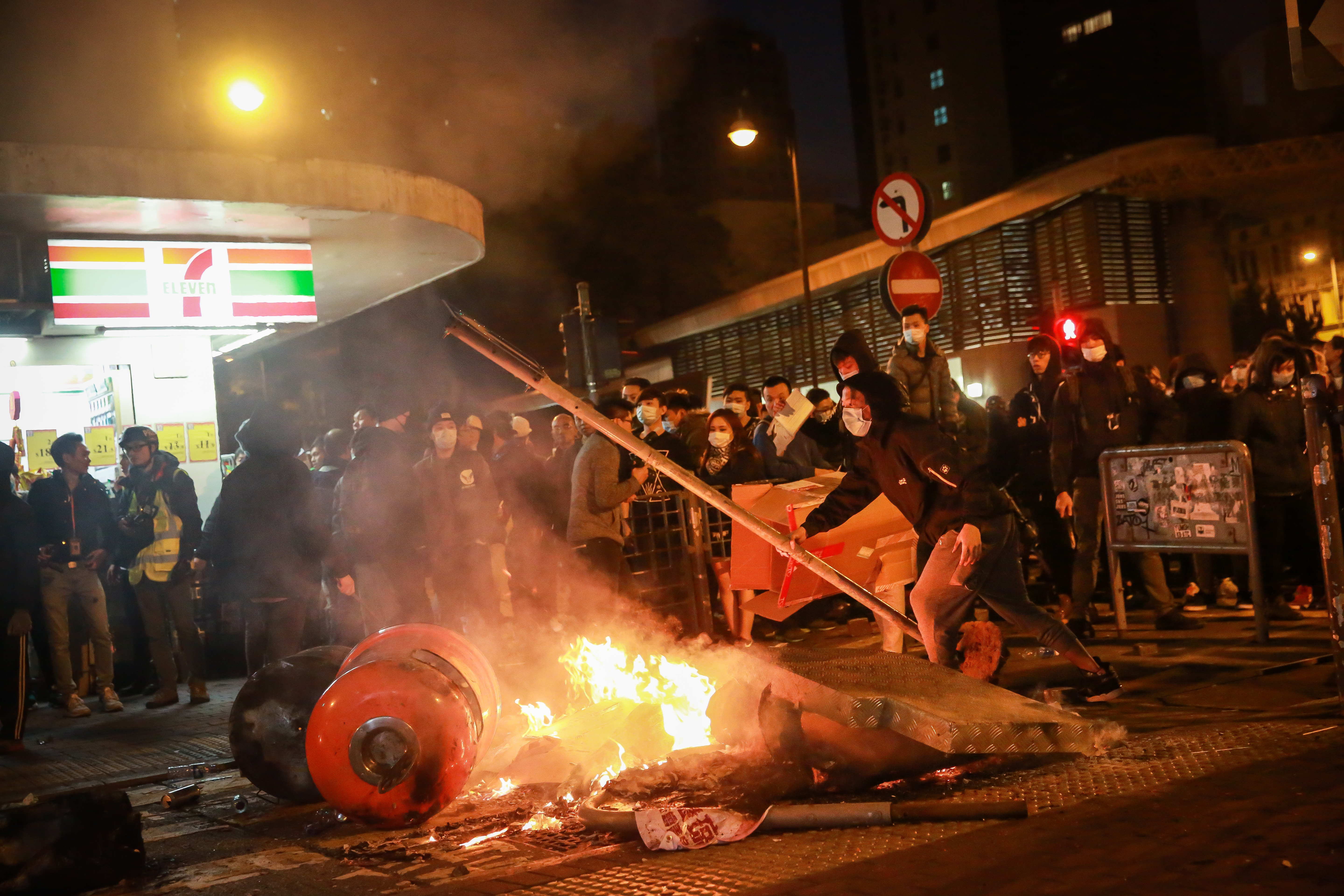 A rioter holds a lamp post as a fire burns in the Mong Kok area of Hong Kong, on Tuesday, Feb. 9, 2016. Rioters set fires and threw bricks at police in Hong Kong early Tuesday, injuring officers and shuttering one of the city's busiest subway stations in a clash over illegal food stalls during the three-day Chinese New Year holiday. Photographer: Billy H.C. Kwok/Bloomberg ORG XMIT: 604115421